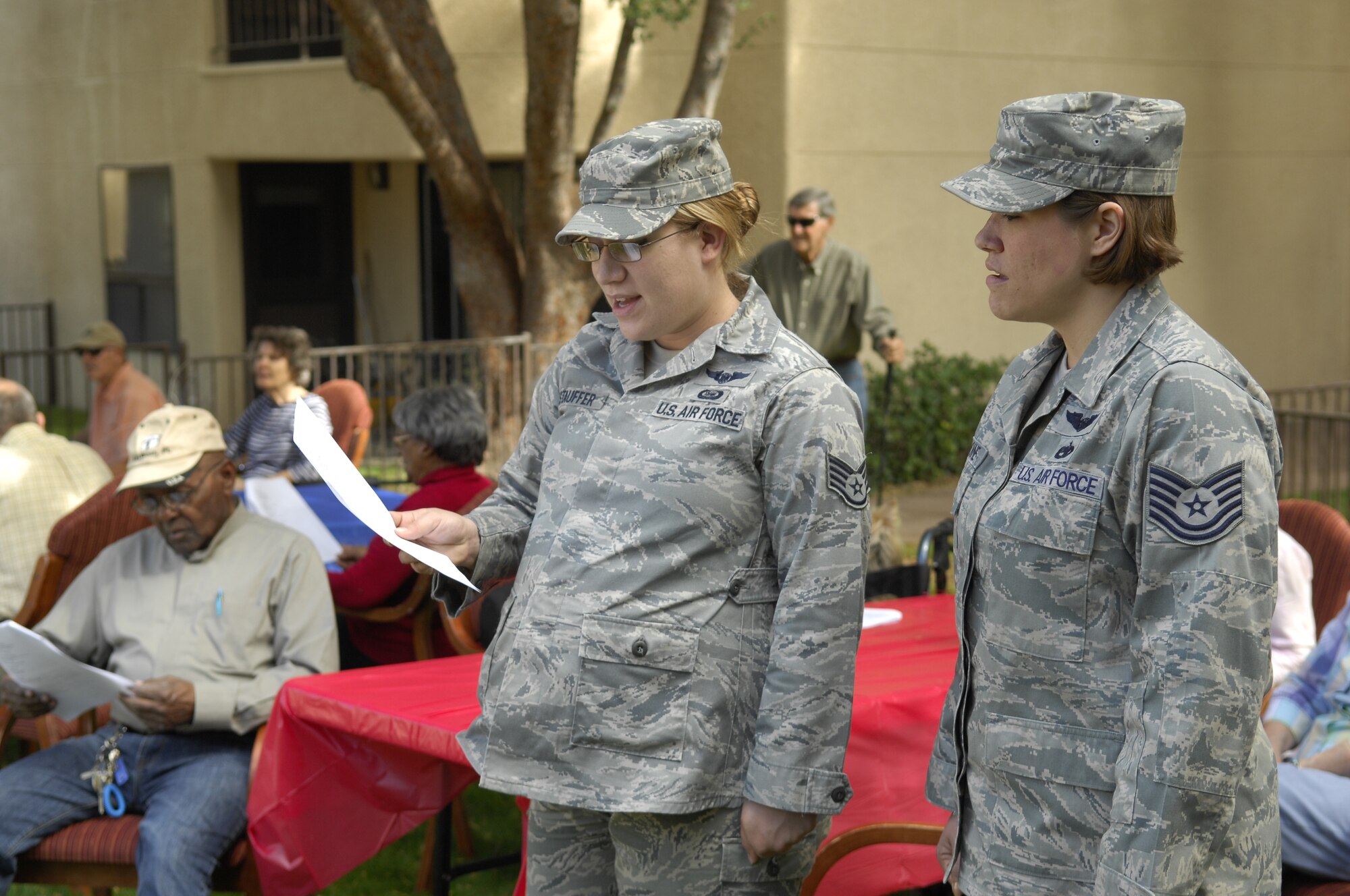 U.S. Air Force Staff Sgt. Christina Stauffer, 41st Electronic Combat Squadron EC-130H Compass Call mission crew supervisor, and Tech. Sgt. Rachel Lemoine, 41st ECS flight engineer, read the lyrics of each service’s songs during a luncheon in honor of veterans in Tucson, Ariz., Nov. 13, 2013. During the ceremony, each veteran was recognized by their branch of service. (U.S. Air Force Photo by Airman 1st Class Betty R. Chevalier/Released)
