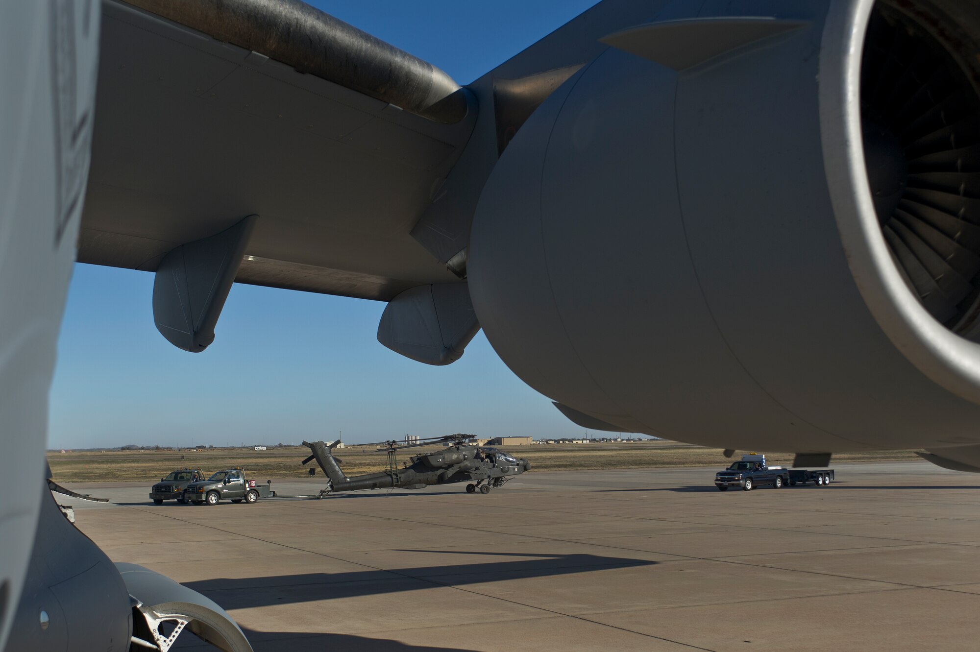 ALTUS AIR FORCE BASE, Okla. – U.S. Air Force maintainers from the 97th Maintenance Directorate tow a U.S. Army AH-64 Apache helicopter across the flightline during joint training Nov. 13, 2013. The U.S. Army and Air Force practiced loading Apache helicopters onto a U.S. Air Force C-17 Globemaster III cargo aircraft to improve joint contingency operations. (U.S. Air Force photo by Senior Airman Dillon Davis/Released)