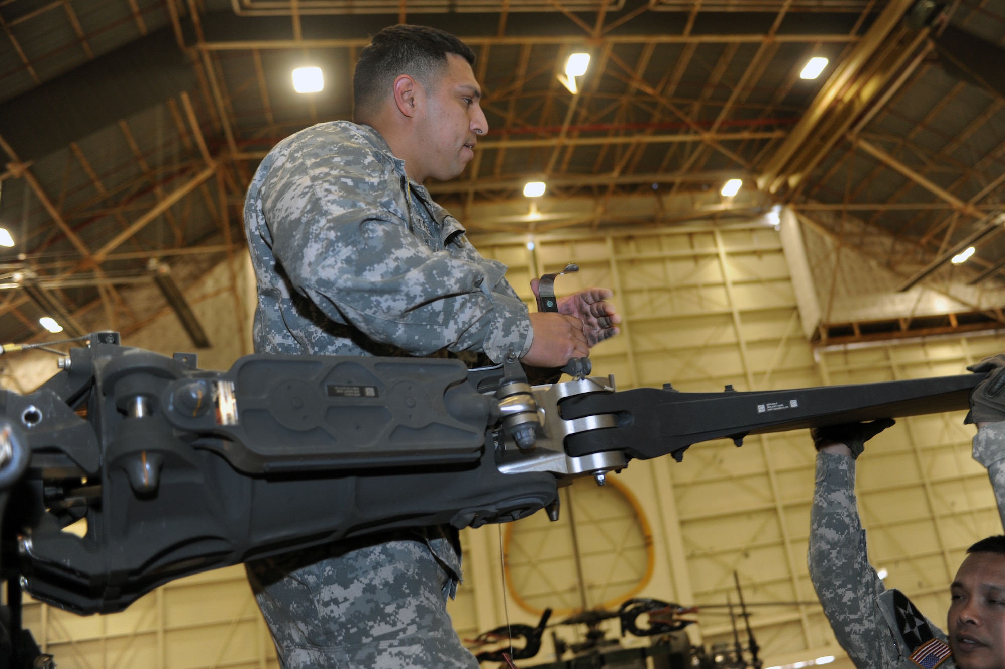 ALTUS AIR FORCE BASE, Okla. – U.S. Army Sgt. Ray Trevino, 1st Battalion, 25th Aviation Regiment, 25th Combat Aviation Brigade AH-64 Apache helicopter maintainer, removes a holding pin from the helicopter’s propeller blade during joint training Nov. 13, 2013. The rotor’s pins must be removed in order to fold back each blade before the aircraft is loaded onto a U.S. Air Force C-17 Globemaster III cargo aircraft. The joint training allowed both service members to practice real-world operations to ensure proficiency during contingency operations. (U.S. Air Force photo by Senior Airman Dillon Davis/Released)