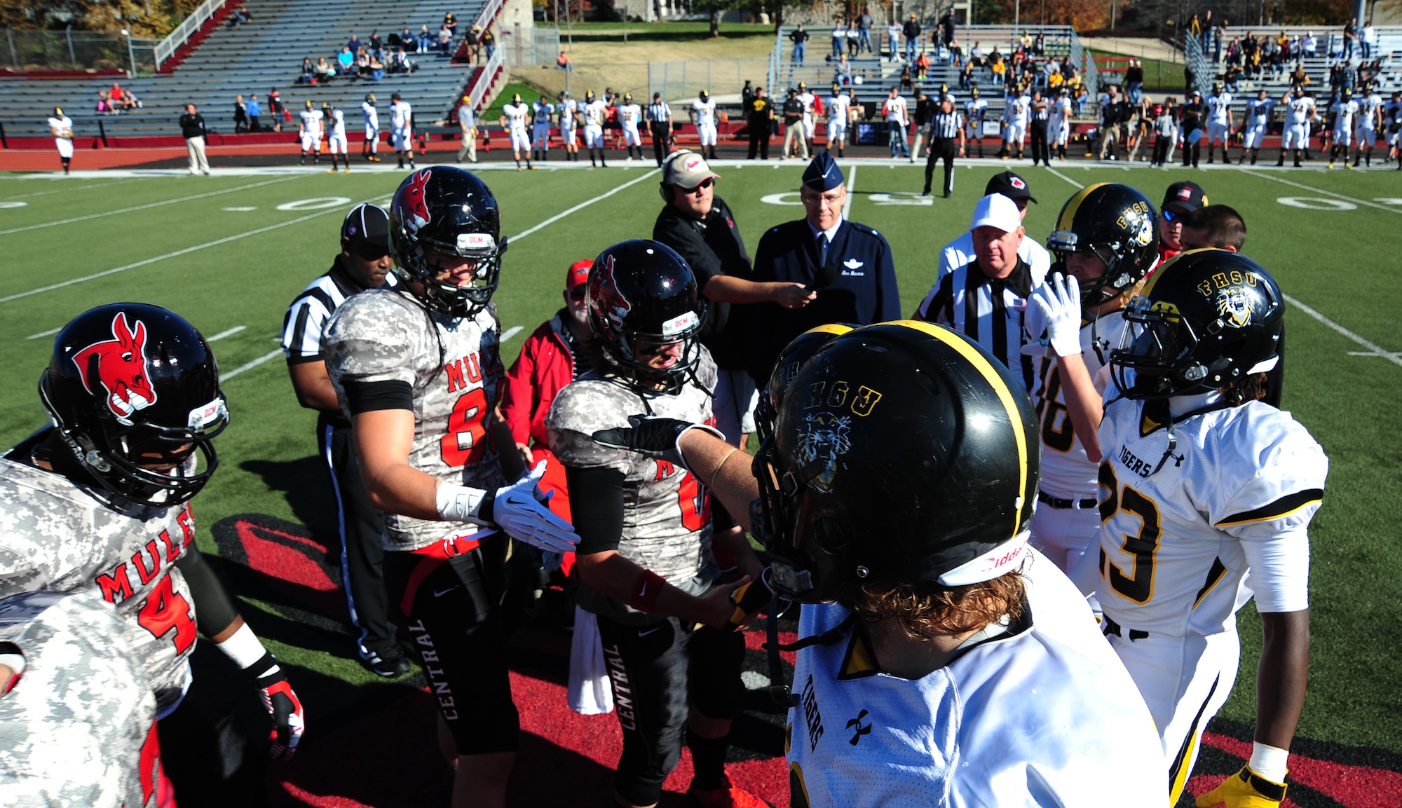 Football players from the University of Central Missouri Mules, left, shake hands with players from the Fort Hays State Tigers before a Military Appreciation Game coin toss at Warrensburg, Mo., Nov. 9, 2013. Each year UCM hosts a military appreciation game to show gratitude to members of the armed forces past and present for serving their country. (U.S. Air Force photo by Staff Sgt. Nick Wilson/Released)