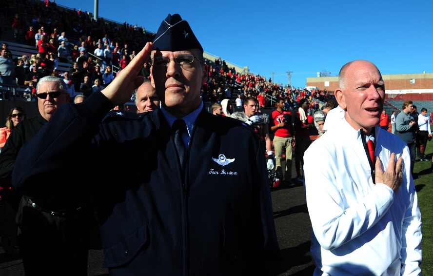 U.S. Air Force Brig. Gen. Thomas Bussiere, 509th Bomb Wing commander, salutes during the playing of the national anthem next to Dr. Charles Ambrose, University of Central Missouri president, before a UCM Mule military appreciation football game, in Warrensburg, Mo., Nov. 9, 2013. Each year UCM hosts a military appreciation game to show gratitude to members of the armed forces past and present for serving their country. (U.S. Air Force photo by Staff Sgt. Nick Wilson/Released)