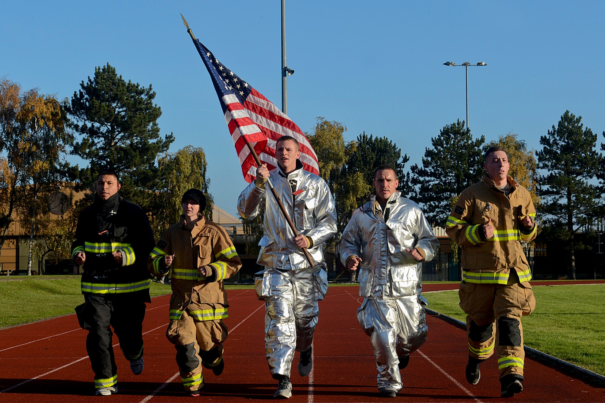 Airmen of the 48th Civil Engineer Squadron Fire Department run with the U.S. flag during the 24-hour Veterans Day vigil run at the Royal Air Force Lakenheath, England, track Nov. 15, 2013. Airmen from the 48th Fighter Wing ran laps in honor of fallen and current veterans. (U.S. Air Force photo by Airman 1st Class Trevor T. McBride)    