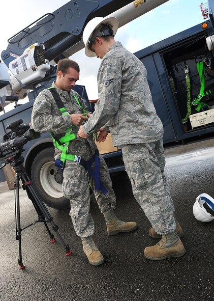 Airman 1st Class Joshua Boone, 786th Civil Engineer Squadron electrical technician, straps Airman 1st Class Thomas Smith, 86th Airlift Wing public affairs broadcaster, into a harness, Nov. 13, 2013. Ramstein Air Base, Germany. 786th CES work more than 480 man-hours climbing flightline light fixtures ranging from 70 to 180 feet in height to keep Ramsteins streets and flightline visible at night. (U.S. Air Force photo/Airman Dymekre Allen)