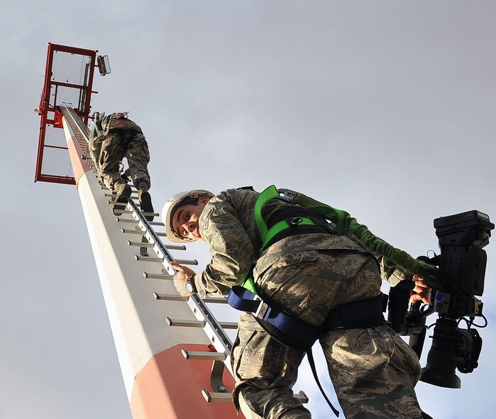 Airman 1st Class Thomas Smith, 86th Airlift Wing public affairs broadcaster and Staff Sgt. Valdir Freitas, 786th Civil Engineer Squadron electrical technician, descend from a flightline light pole after repairing light bulbs, Nov. 13, 2013, Ramstein Air Base, Germany. 786th CES work more than 480 man-hours climbing flightline light fixtures ranging from 70 to 180 feet in height to keep Ramsteins streets and flightline visible at night. (U.S. Air Force photo/Airman Dymekre Allen)