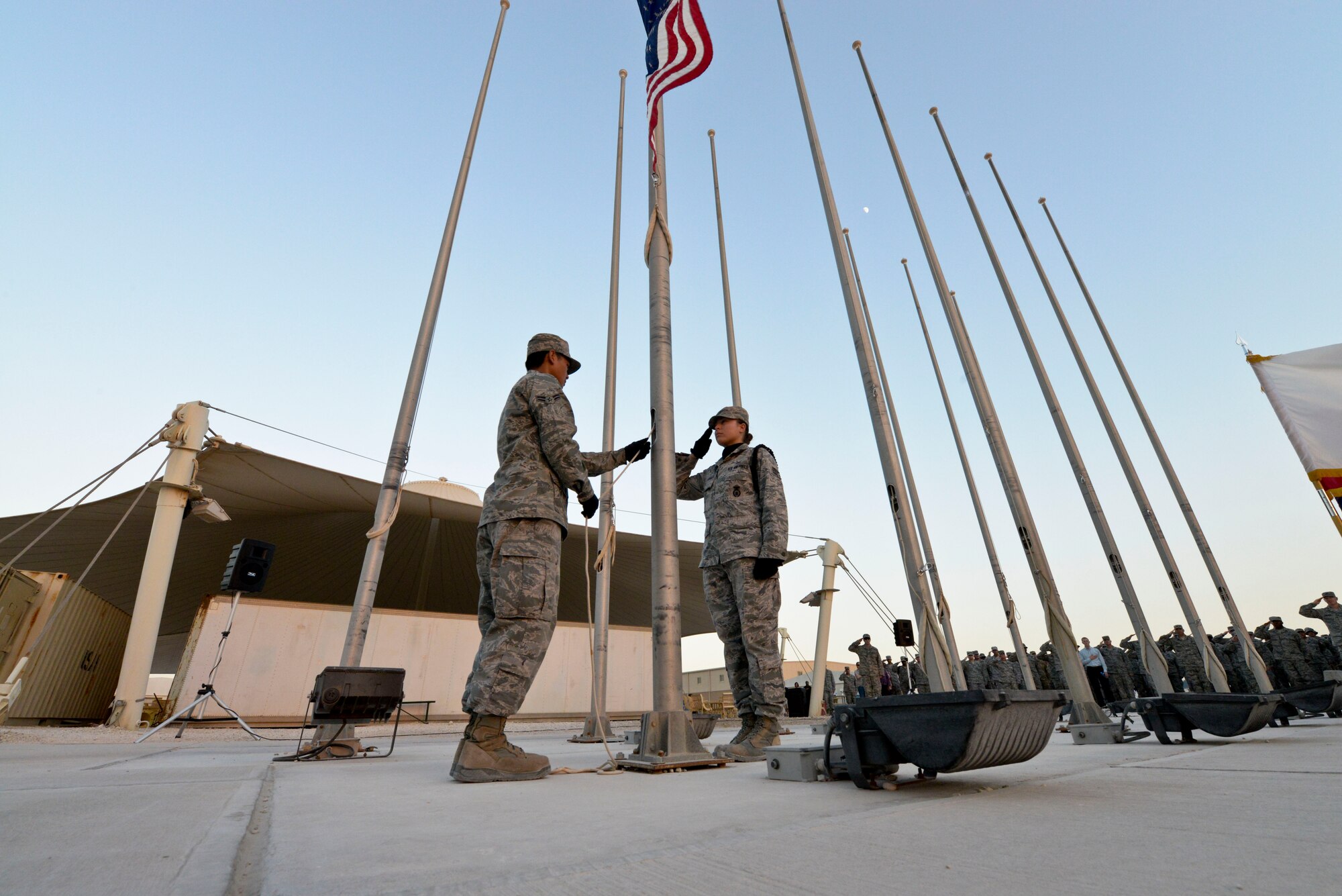 Airman 1st Class Kenneth Caberto lowers the U.S. flag while Senior Airman Raychelle Goldsmith salutes during the 379th Air Expeditionary Wing Veterans Day retreat ceremony in Southwest Asia, Nov. 11, 2013. U.S. and coalition partners attended the retreat ceremony to honor former and current veterans. Caberto is a 379th Expeditionary Logistics Readiness Squadron central repair facility apprentice deployed from Pope Army Airfield, N.C., and hails from  Salinas, Calif.  Goldsmith is a 379th Expeditionary Security Forces Squadron journeyman and is deployed from Eglin Air Force Base, Fla., and is a Newport News, Va., native. (U.S. Air Force photo/Tech. Sgt. Joselito Aribuabo)
