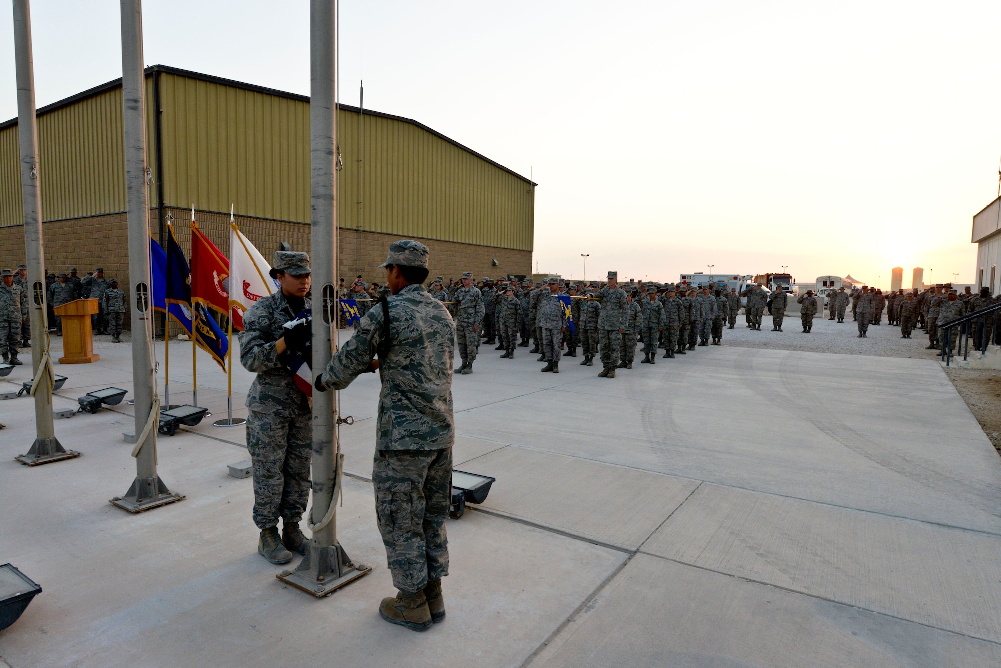 Senior Airman Raychelle Goldsmith and Airman 1st Class Kenneth Caberto prepare to fold the U.S. flag during the 379th Air Expeditionary Wing Veterans Day retreat ceremony in Southwest Asia, Nov. 11, 2013. Goldsmith is a 379th Expeditionary Security Forces Squadron journeyman and is deployed from Eglin Air Force Base, Fla., and is a Newport News, Va., native. Caberto is a 379th Expeditionary Logistics Readiness Squadron central repair facility apprentice deployed from Pope Army Airfield, N.C., and hails from  Salinas, Calif.  (U.S. Air Force photo/Tech. Sgt. Joselito Aribuabo)