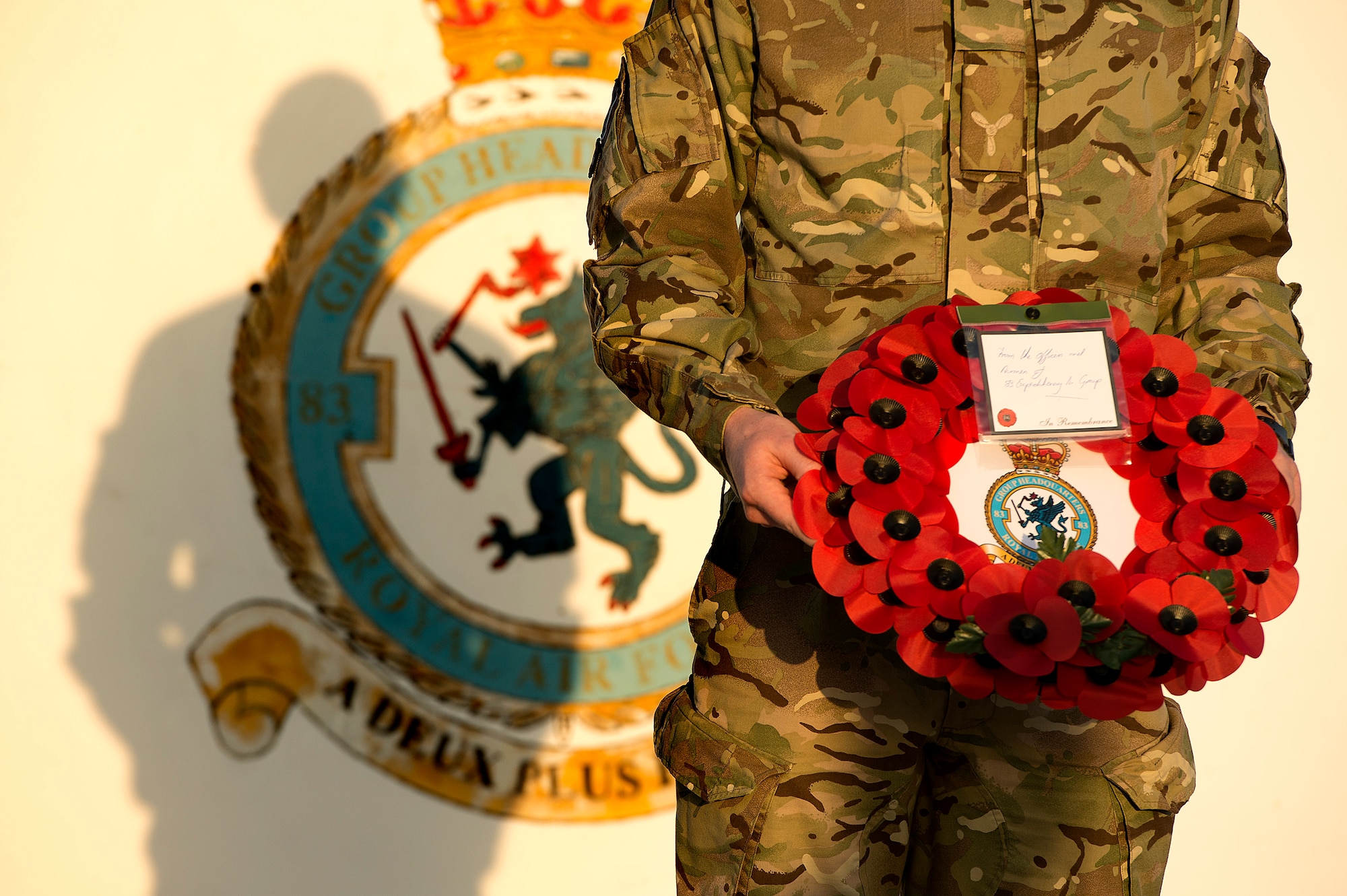 A Royal Air Force senior aircraftsman holds a poppy wreath during a sunset remembrance ceremony at the 83rd Expeditionary Air Group headquarters Nov. 9, 2013. The RAF's 83 EAG is responsible for all English units operating in Afghanistan and the Middle East. (USAF Photo by Master Sgt. Ben Bloker)
