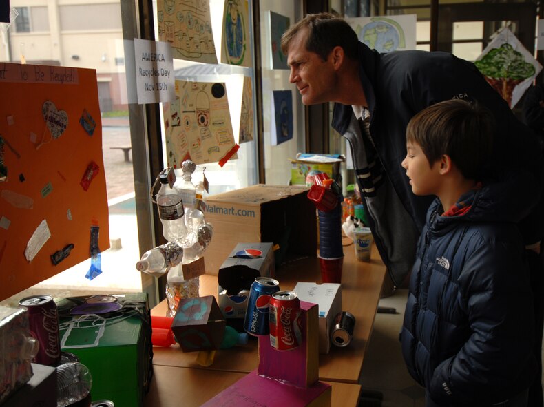 Michael Destin and son, Michael, check out the recycled art display at Osan Air Base, Republic of Korea, Nov. 14, 2013. The art projects were used to commemorate America Recycles Day, which is a day set aside to raise recycling awareness and identify the benefits of making resources available to future generations. (U.S. Air Force photo/1st Lt. Kay M. Nissen)
