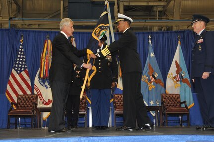 Admiral Cecil Haney accepts the U.S. Strategic Command colors from Secretary of Defense Chuck Hagel, as outgoing commander General C. Robert Kehler looks on, during the U.S. Strategic Command change of command ceremony at Offutt Air Force Base, Omaha, Nebraska Nov. 15, 2013. (Photo by Steve Cunningham / Released)