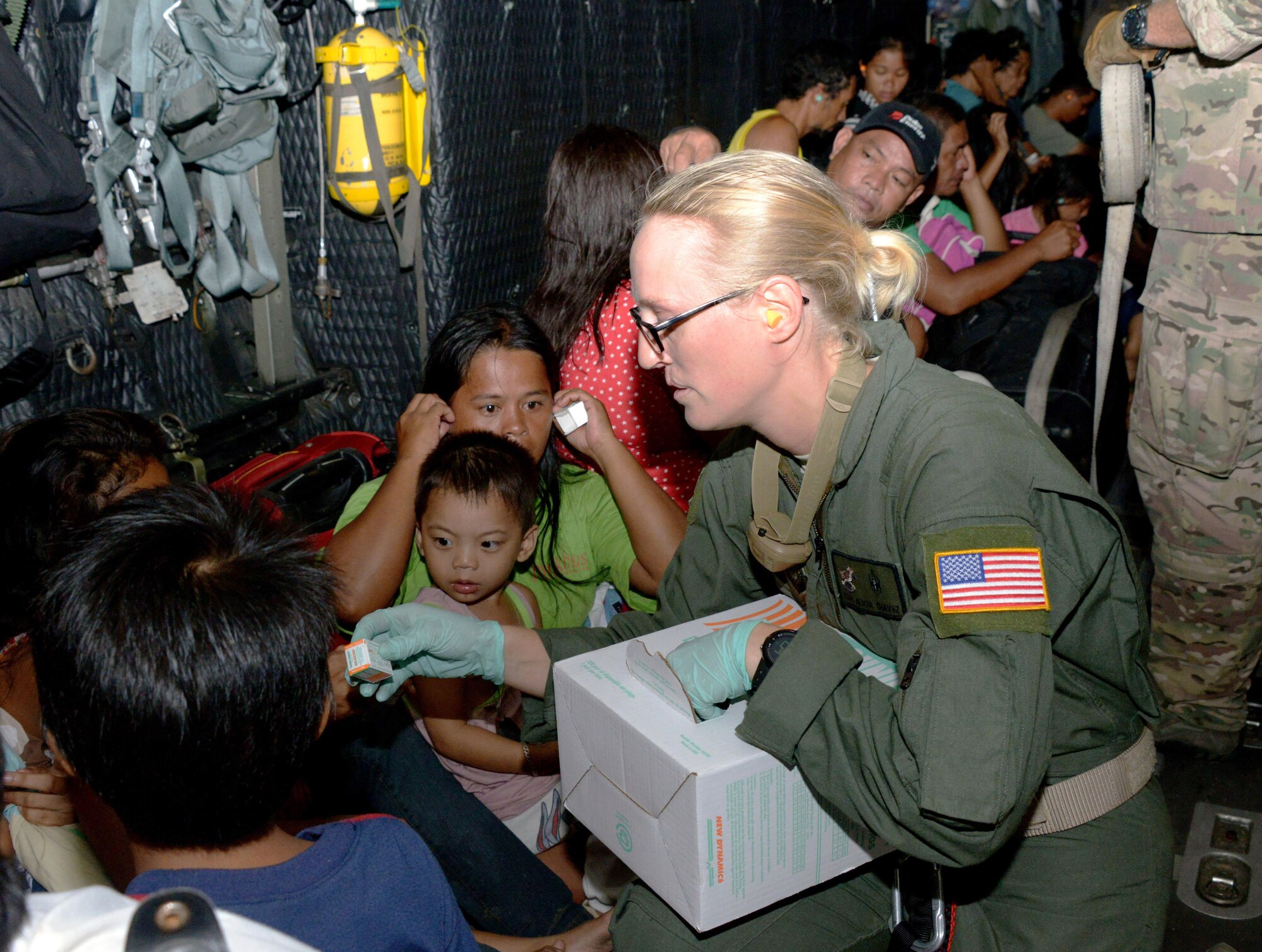 Staff Sgt. Alicia Chavez passes out ear plugs to displaced people onboard an MC-130P Combat Shadow Nov. 14, 2013, as they are transported from Tacloban Airport to Manila, Philippines. Air Force Special Operations Command Airmen are deployed in support of Operation Damayan, enabling night operations to facilitate the flow of aid. The role of U.S. military forces during any foreign humanitarian assistance event is to rapidly respond to mitigate human suffering and prevent further loss of life. Chavez is a 353rd Special Operations Support Squadron independent duty medical technician. (U.S. Air Force photo/Tech. Sgt. Kristine Dreyer)