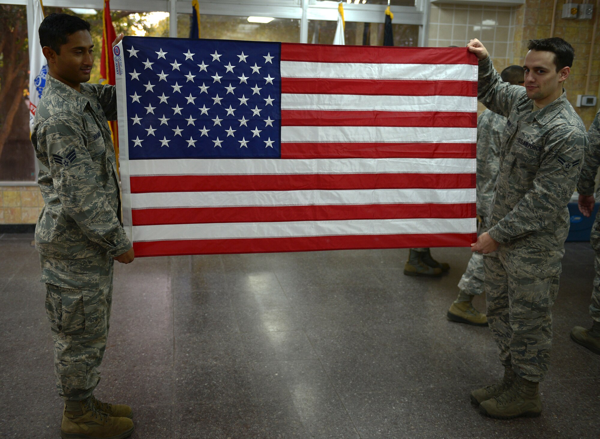 Senior Airman Ariful Haque and Airman 1st Class Class Austin Webb, members of the Yokota Air Base Honor Guard, fully extend a United States flag at Yokota Air Base, Japan, Nov. 13, 2013. The flag can only be folded into the traditional triangle after all wrinkles and creases are removed.  . (U.S. Air Force photo by Airman 1st Class David Danford/Released)