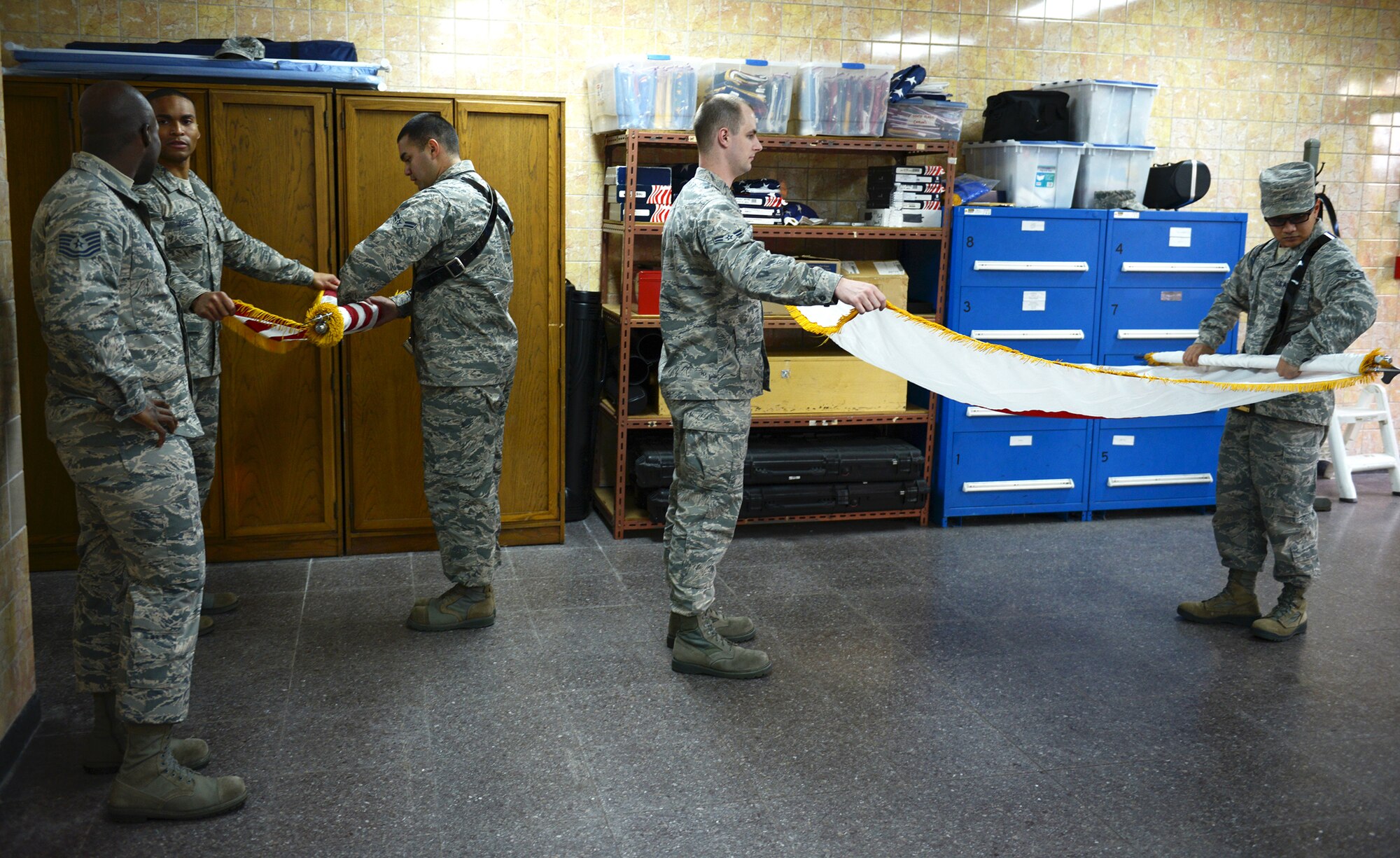 Members of the Yokota Air Base Honor Guard roll flags at Yokota Air Base, Japan, Nov. 13, 2013. When not used in training, the flags are stored in a cylindrical container to protect them from damage. (U.S. Air Force photo by Airman 1st Class David Danford/Released)
