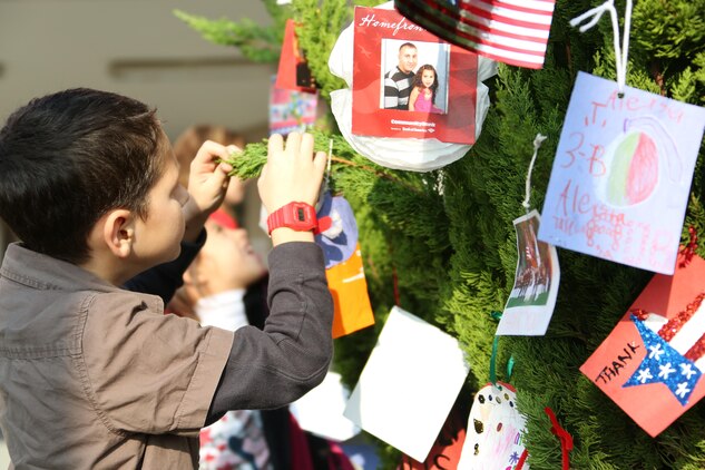Jeremy Uhl, 8, hangs his ornament on the tree outside of Matthew C. Perry Elementary School aboard Marine Corps Air Station Iwakuni, Japan, during the Veterans Day ceremony Nov. 6, 2013. Landrum acknowledged all veterans who work for M.C. Perry by giving them a special dog tag designed as the American flag.