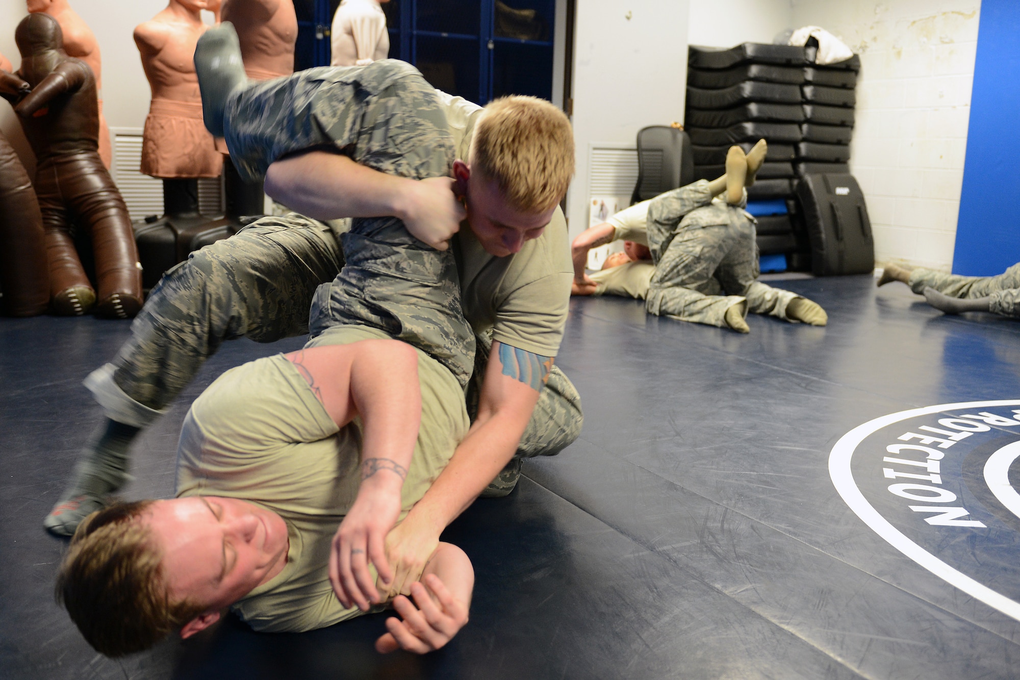 Senior Airman Brandon Reid, 62nd Aerial Port Squadron ramp services member, grapples with Senior Airman Joshua Drake, 62nd APS aircraft service element member, during a 627th Security Forces Squadron Phoenix Raven self-defense course, Nov. 14, 2013, at Joint Base Lewis-McChord, Wash. Airmen participating in the course learned hand-to-hand combat, verbal defense, ground fighting, and weapons take-aways skills. (U. S. Air Force photo/Airman 1st Class Jacob Jimenez) 