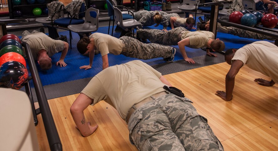 U.S. Air Force Airmen from the 23d Wing Public Affairs office do pushups during combat bowling for Comprehensive Airman Fitness Day at Moody Air Force Base, Ga., Nov. 15, 2013. When a member of the opposing team scored a strike, everyone did 10 pushups. (U.S. Air Force photo by Airman 1st Class Alexis Grotz/Released)