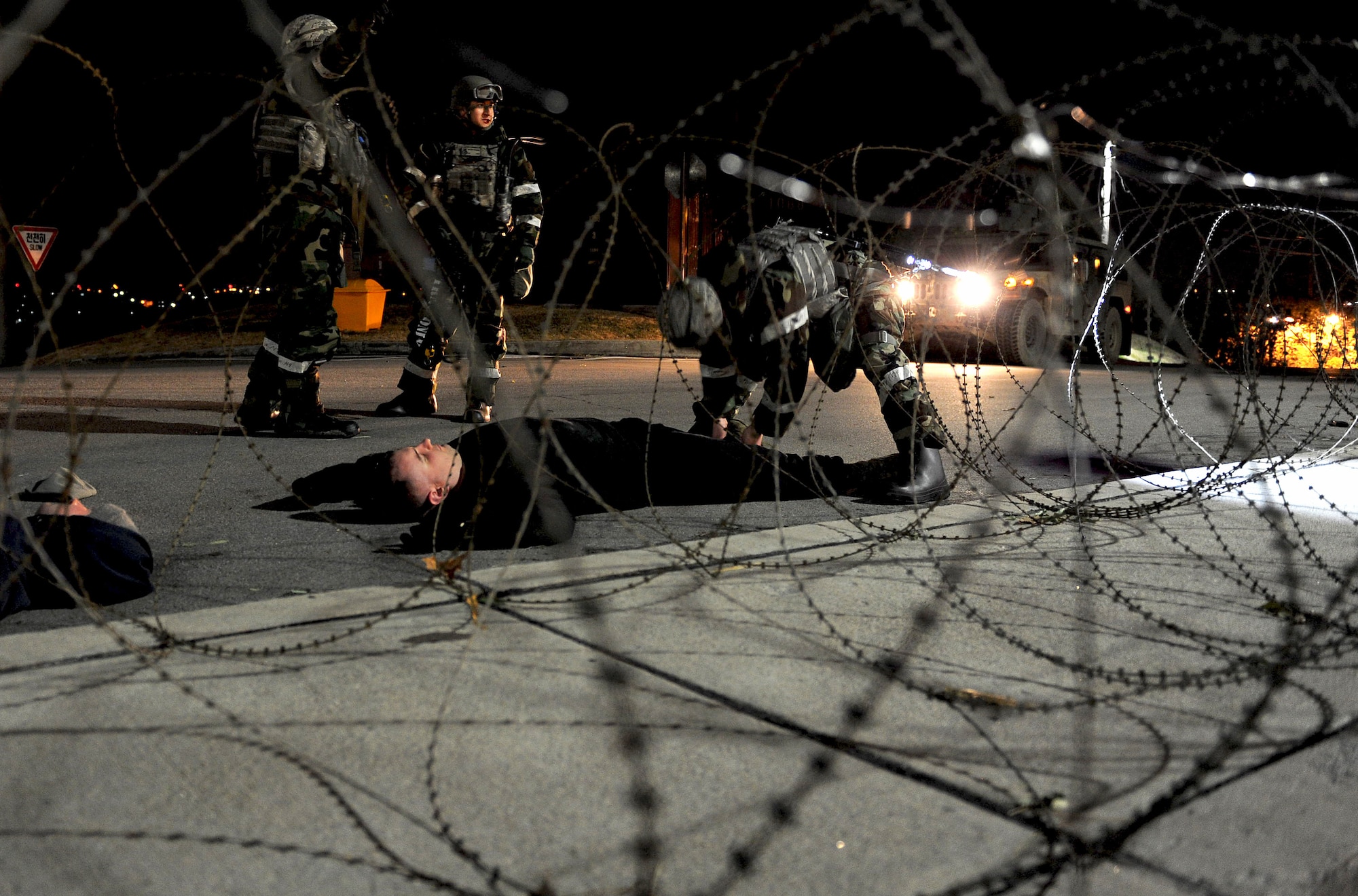 Airmen from the 51st Security Forces Squadron form a human cordon while another defender inspects a simulated opposition forces member casualty during Operational Readiness Exercise Beverly Bulldog 14-01 at Osan Air Base, Republic of Korea, Nov. 19, 2013. The casualties were searched for any potentially hazardous materials or weapons. (U.S. Air Force photo/Staff Sgt. Sara Csurilla)