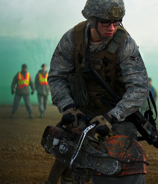 Airman 1st Class Patrick Wagenecht, 91st Security Support Squadron tactical response force member simulates using an electric saw during a recapture, recovery exercise, Nov. 14, 2013. The exercise is used as a training tool to evaluate the responding forces, their reaction of denying access to the resource from hostile actions, and recovery of the resource if access is gained. (U.S. Air Force photo/Senior Airman Brittany Y. Auld)