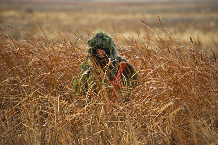 An Airman from the 91st Security Forces Group hides in tall grass during a recapture, recovery exercise, Nov. 14, 2013. The exercise is used as a training tool to evaluate the responding forces, their reaction of denying access to the resource from hostile actions, and recovery of the resource if access is gained. (U.S. Air Force photo/Senior Airman Brittany Y. Auld) 