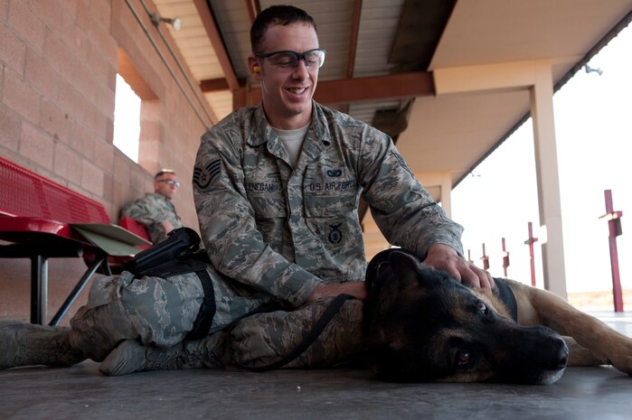 U.S. Air Force Staff Sgt. Matthew Lenegan, 99th Security Force Squadron military working dog handler, praises his MWD Nero for a good performance after taking part in the MWD Course of Fire Nov. 15, 2013, at Nellis Air Force Base, Nev. The purpose of the course is to expose the canine to the sound of gunfire and evaluate their behavior to avoid mishaps during real-world combat operations. (U.S. Air Force photo by Airman 1st Class Joshua Kleinholz)