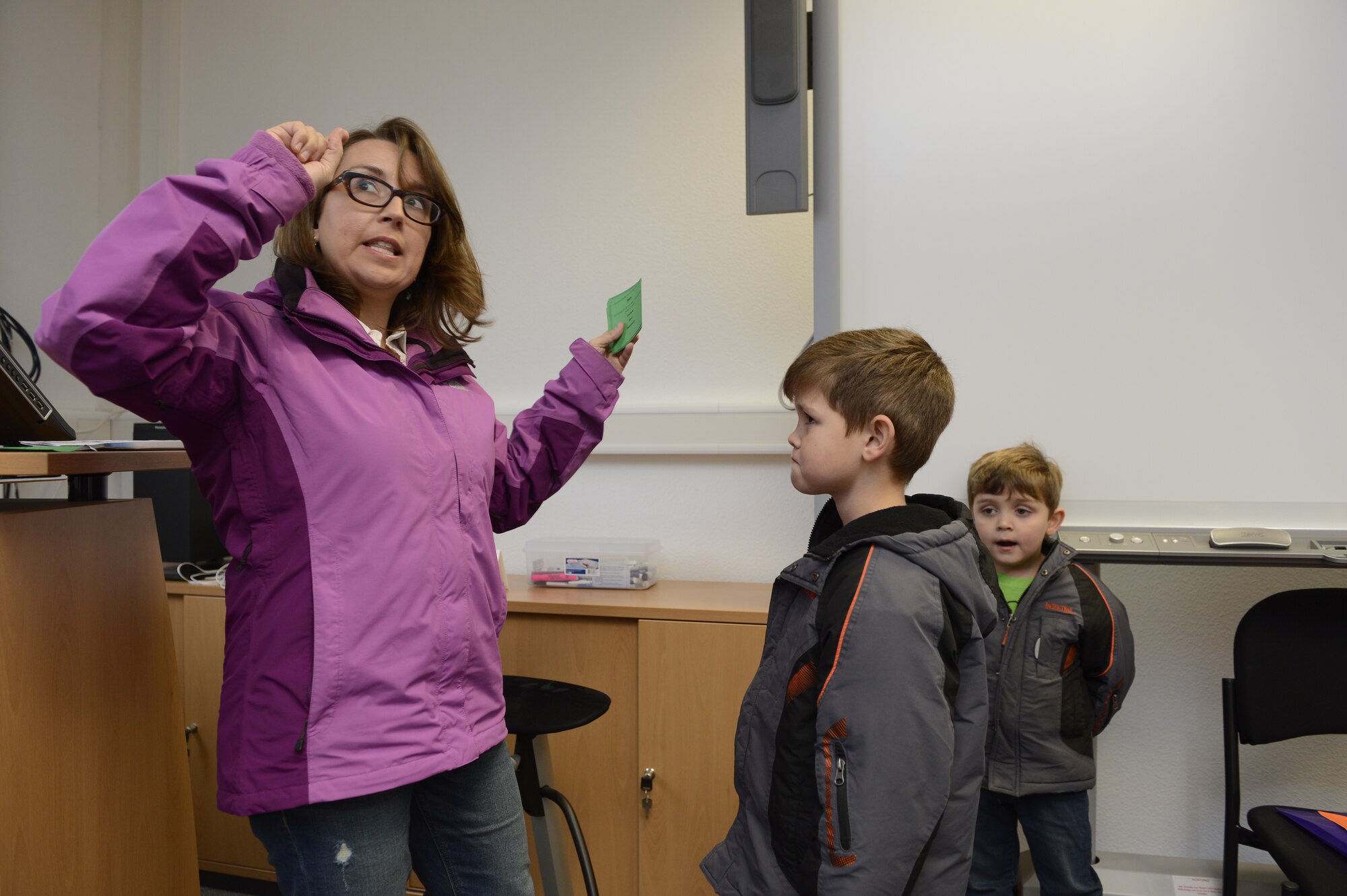 SPANGDAHLEM AIR BASE, Germany—Lee McDonough, a military spouse, left, acts out a taboo game card with her sons John, center, and Benjamin, right, to gain points during the Airman & Family Readiness Center scavenger hunt Nov. 16, 2013. For some items, families had to play games for a chance to win bonus points toward winning the scavenger hunt. (U.S. Air Force photo by Staff Sgt. Christopher Ruano/Released)