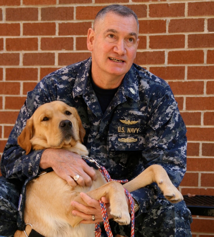 Navy Capt.(Dr.) Robert Koffman, psychiatrist and chief clinical consultant at the National Intrepid Center of Excellence on the campus of Walter Reed National Military Medical Center in Bethesda, Md., says his newly graduated therapy dog, Ron, the mascot at the center, is therapeutic for patients with traumatic brain injury, post-traumatic stress disorder and for staff and caregivers. Petting a dog releases the hormone oxytocin, which calms both the human and the dog, he said. DOD photo by Terri Moon Cronk