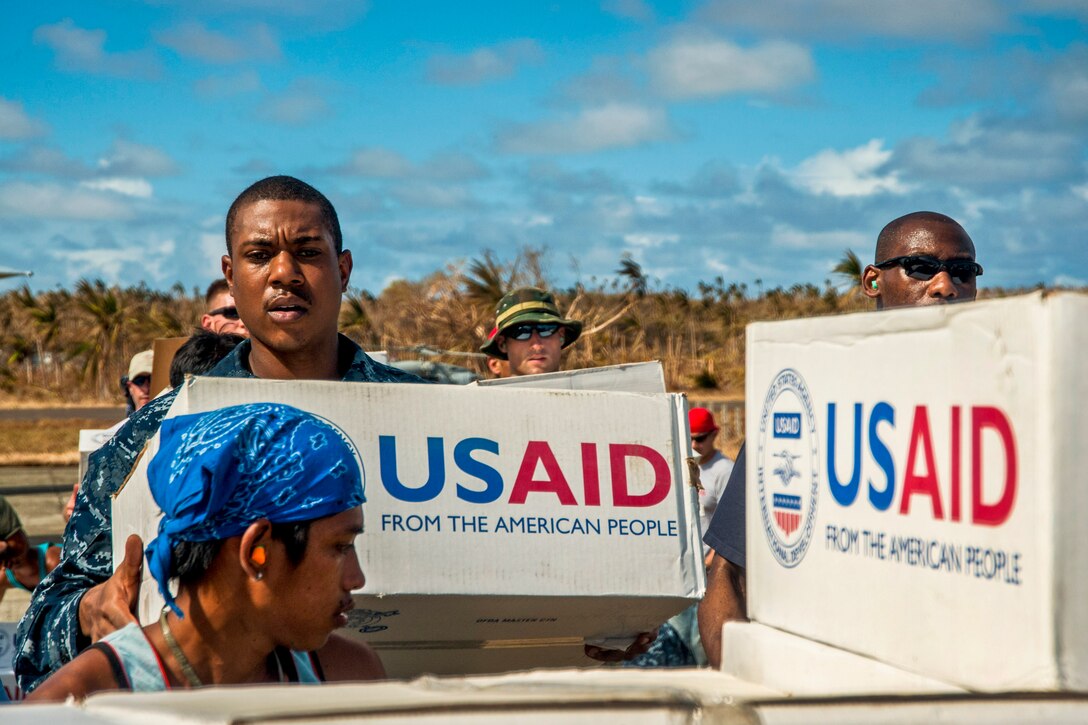 U.S. Navy Seaman Quinton Dotson, left, other U.S. troops and Philippine citizens unload relief supplies to support Operation Damayan in Guiuan, Philippines, Nov. 17, 2013. Dotson, a hospital corpsman, is assigned to the aircraft carrier USS George Washington.