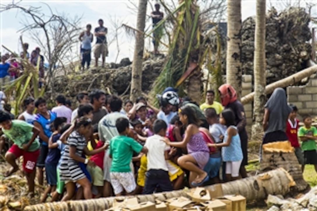 U.S. Navy Petty Officer 3rd Class William Casson talks with children after dropping supplies from an SH-60B Seahawk from Helicopter Anti-Submarine Squadron Light 49, assigned to the guided-missile cruiser USS Cowpens, during Operation Damayan in Tacloban, Philippines, Nov. 17, 2013. Casson is a naval aircrewman. The Cowpens is with George Washington Strike Group supporting the 3rd Marine Expeditionary Brigade.