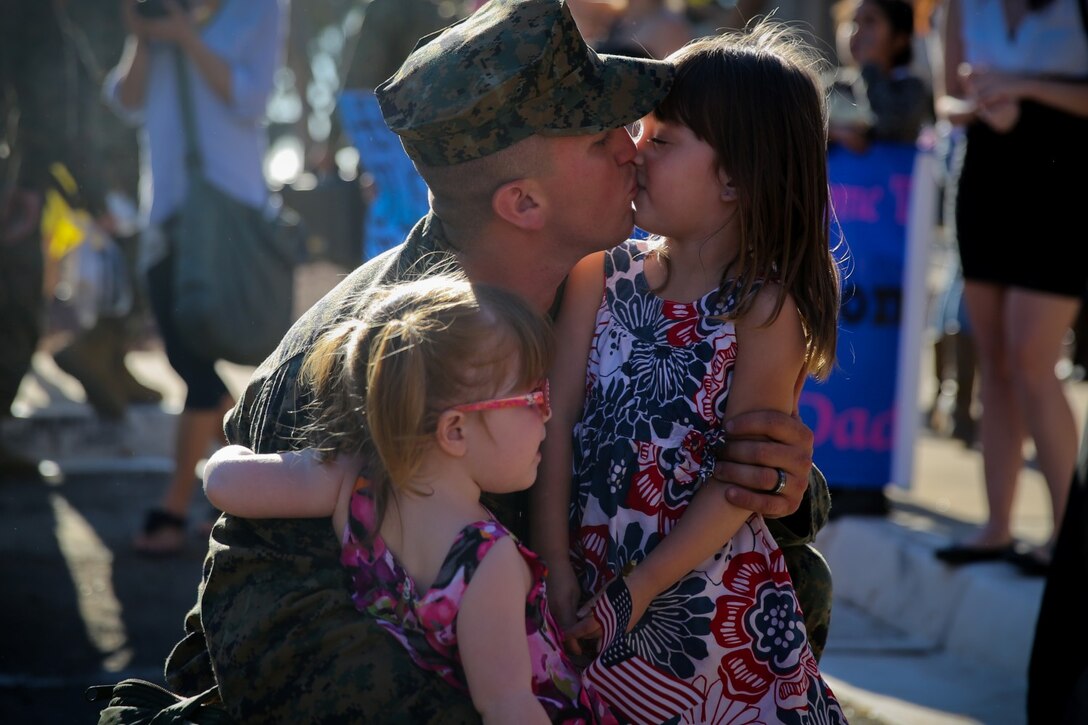 A Marine with Bravo Company, 3rd Assault Amphibian Battalion, greets his two daughters at the company’s homecoming here, Nov. 14, 2013. The Marines returned after being away for six months to Okinawa, Japan, as part of the Unit Deployment Program. The company conducted a variety of training including an officer exchange program with the Japanese military. This allowed Marines to interact with and teach Japanese officers about the Marine Corps’ capabilities.
