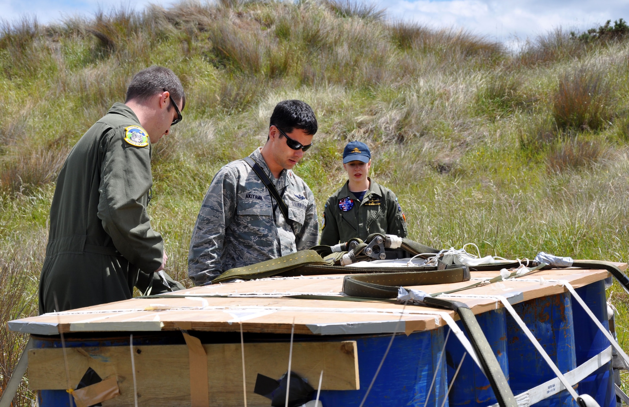 OHAKEA, New Zealand -- (Left to right) United States Air Force Staff Sgt. Robert Gallagher and Maj. Corey Akiyama demonstrate U.S. Air Force protocols for checking the integrity of dropped cargo for Royal New Zealand Air Force Pilot Officer Emma Taylor (right) as she earns her U.S. Air Force drop zone safety officer certification during Exercise Kiwi Flag Nov. 14 at the New Zealand Defence Force Raumi Drop Zone near Ohakea, New Zealand. Kiwi Flag personnel are supporting Exercise Southern Katipo -- held on New Zealand’s South Island -- by managing air operations and providing cargo and passenger airlift including tactical air drops to SK participants. SK hosts nine countries involved in air, land and maritime operations. (U.S. Air Force photo by Senior Master Sgt. Denise Johnson)