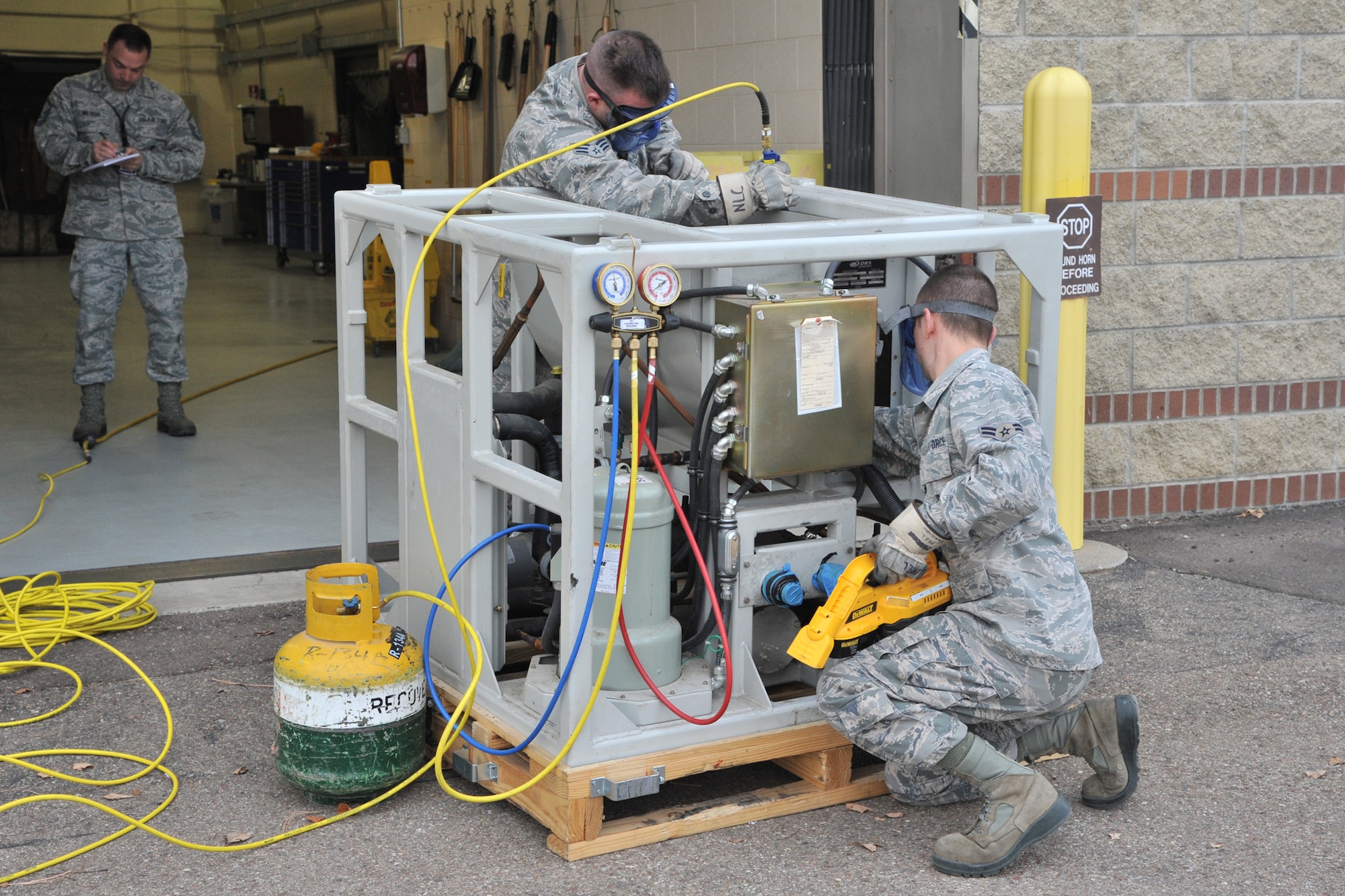 Two Airmen from the 341st Maintenance Operations Squadron Power, Refrigeration and Electrical Section, follow a technical order to complete a task as a member of the Air Force Global Strike Command Inspector General team evaluates them in the background Nov. 14. The 341st Missile Wing was awarded an overall “Excellent” rating following a weeklong Nuclear Operational Readiness Inspection Nov. 12 to 18. (U.S. Air Force photo/John Turner)
