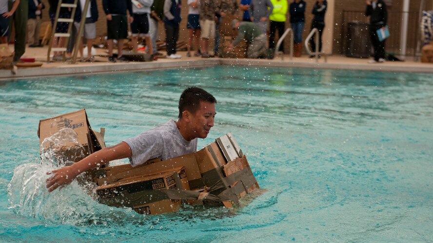 A member of Team Holloman attempts to traverse the pool in the team build-your-own boat race as part of Sports Day at Holloman Air Force Base, N.M., Nov. 15. Sports Day is an annual event held through the Domenici Fitness and Sports Center, in which Holloman units to compete against one another in various team and individual events. (U.S. Air Force photo by Airman 1st Class Aaron Montoya/Released)