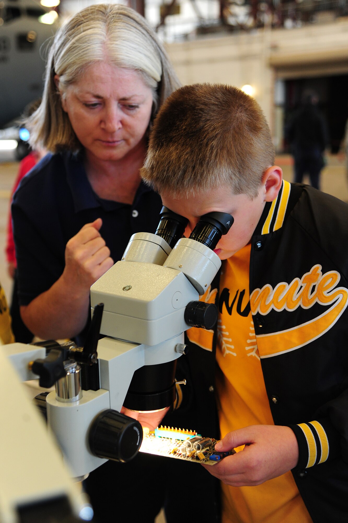 ALTUS AIR FORCE BASE, Okla. -- Dawn Tabor, 97th Maintenance Directorate avionics technician, shows fifth-grader Tyler Janning how to use a microscope to identify blown out fuses during the Burns Flat STARBASE Career Day Nov. 18, 2013. Approximately 75 fifth-grade students visited various base agencies to see how science, technology, engineering and math are applied to jobs in the military. The STARBASE program aims to motivate students to explore STEM as they continue their education. (U.S. Air Force photo by Senior Airman Lausanne Genuino/Released)