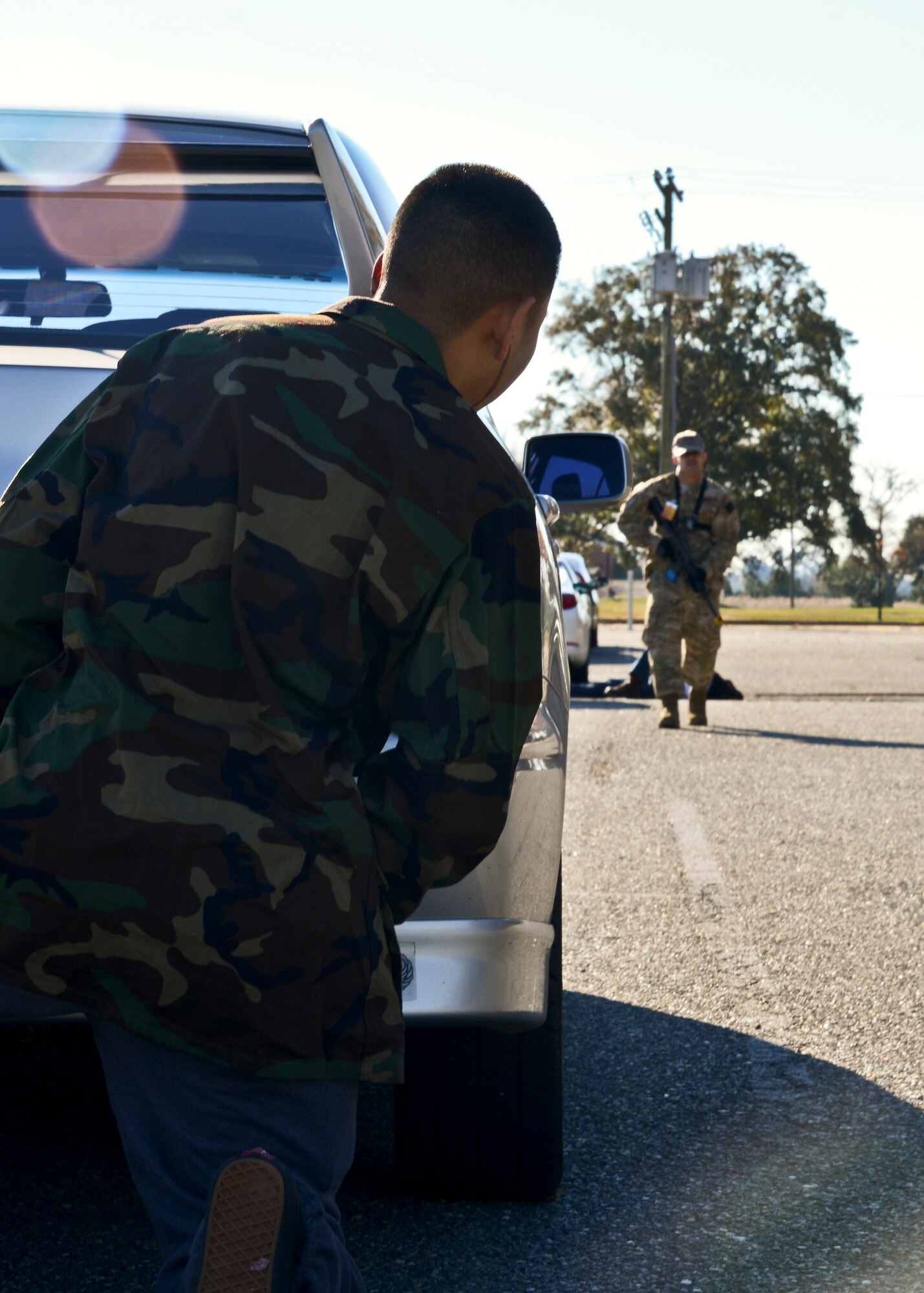 U.S. Air Force Airman 1st Class Putthaporn Boonpreda, 633rd Civil Engineer Squadron air terminal representative, hides behind a vehicle during an active-shooter exercise at Langley Air Force Base, Va., Nov. 19, 2013. The exercise aimed to prepare Langley personnel for an active-shooter threat. (U.S. Air Force photo by Airman 1st Class Victoria H. Taylor/Released)