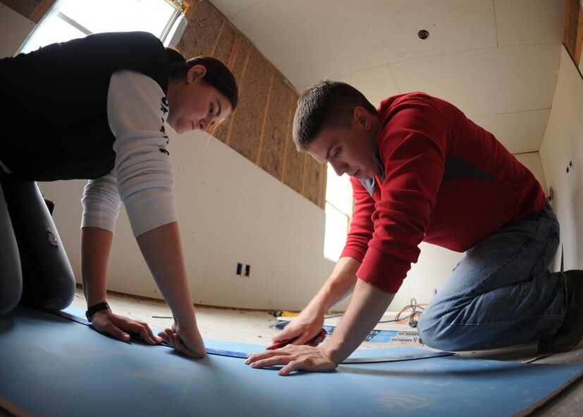 U.S. Air Force Airman 1st Class Erica Butler, left, and Airman 1st Class Tyler Lamb, both assigned to the 7th Operations Support Squadron, measure and cut a piece of sheetrock Nov. 14, 2013, in Abilene, Texas. Airmen from the 7th OSS took time out of their day to volunteer at a worksite in the Abilene community. At this particular site, Habitat for Humanity is working on building three homes. (U.S. Air Force photo by Senior Airman Shannon Hall/Released)
