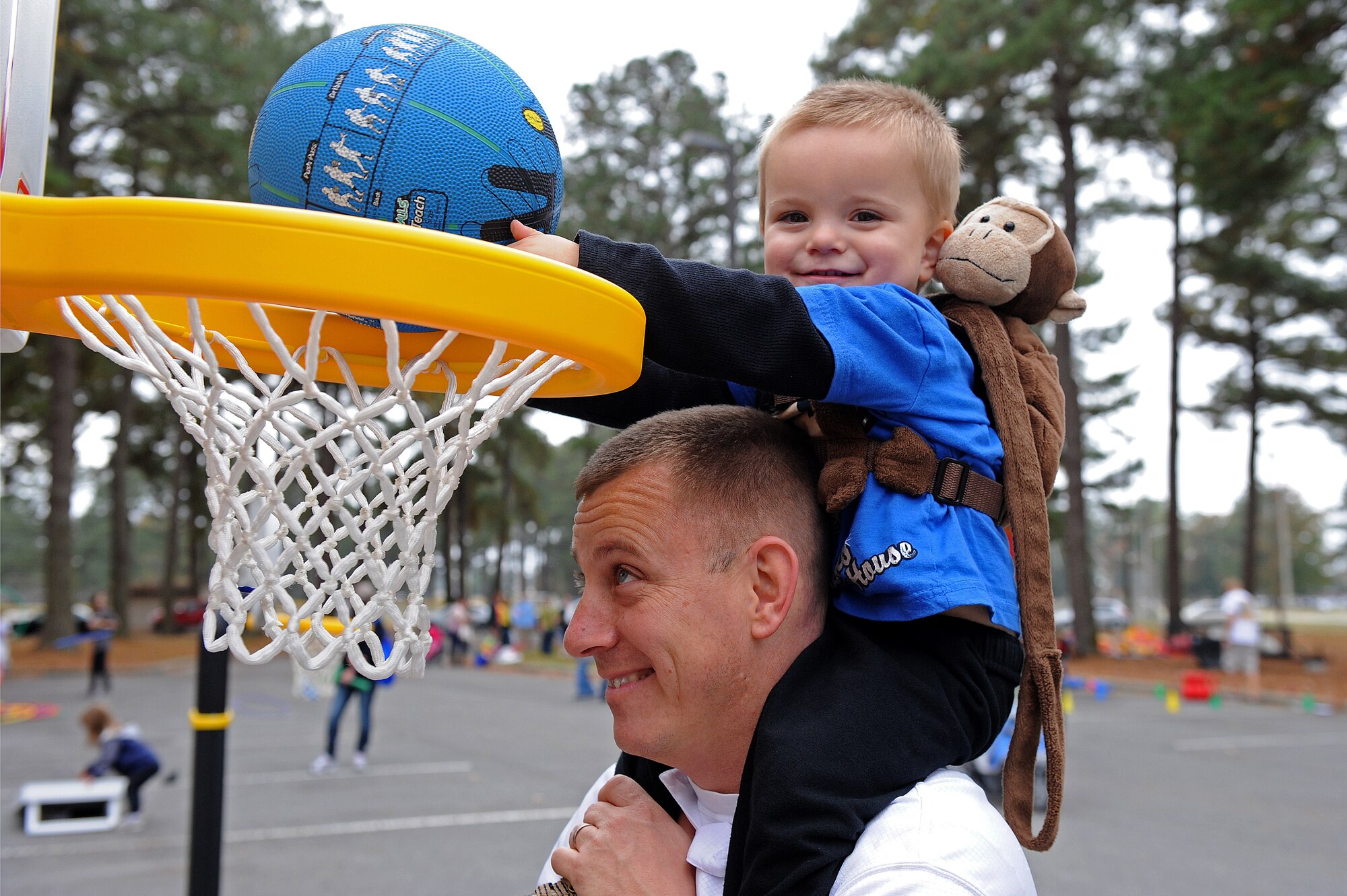 U.S. Air Force Master Sgt. Travis Clawson, 4th Civil Engineer Squadron systems fire chief, hoists his son to make a basket during the Month of the Military Family block party at Seymour Johnson Air Force Base, N.C., Nov. 16, 2013. The event featured stations for children to get involved, including basketball, corn hole and an oversized checker board. (U.S. Air Force photo by Airman 1st Class Aaron J. Jenne)