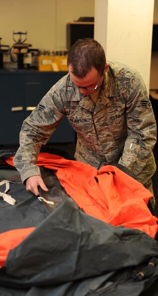 U.S. Air Force Senior Airman Eric Blanton, 7th Operations Support Squadron, flattens out a life raft after performing an inspection Nov. 18, 2013, at Dyess Air Force Base, Texas. Blanton must perform his daily duties as an Aircrew Flight Equipment technician, in addition to battling his type-one diabetes by eating the right foods to maintain his glucose levels. (U.S. Air Force photo by Airman 1st Class Autumn Velez/Released)