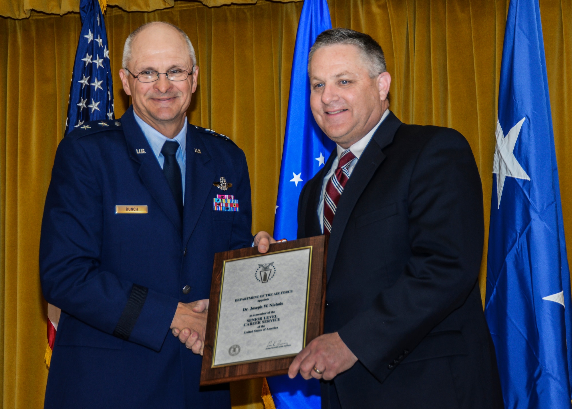 Maj. Gen. Arnold Bunch Jr., Air Force Test Center commander, presents Dr. Joseph Nichols with a plaque on the occasion of his appointment as a member of the Senior Level Career service of the United States of America. (U.S. Air Force photo by Rebecca Amber)