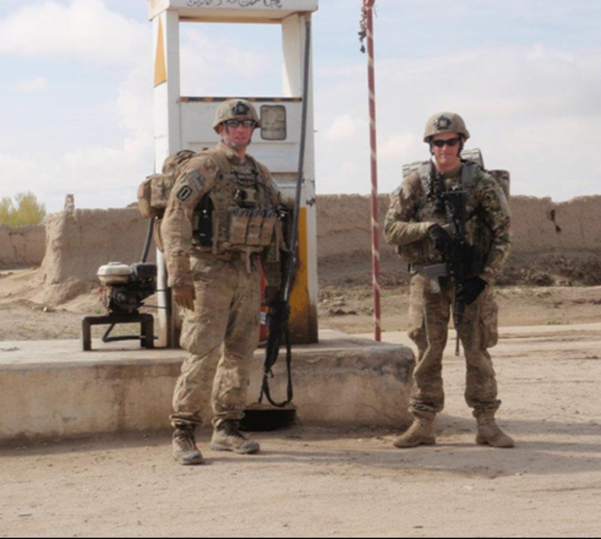 U.S. Air Force Master Sgt. Tracy Passerotti, 4th Civil Engineer Squadron explosive ordnance disposal (EOD) NCO in-charge of logistics, and Senior Airman Justin Beasley, 4th CES EOD technician, stand near a refueling pump during a recent deployment to Afghanistan.  Passerotti and Beasley were part of the three-man team whose vehicle ran over an improvised explosive device, injuring Beasley and leading to him being awarded the Purple Heart.  (Courtesy photo)
