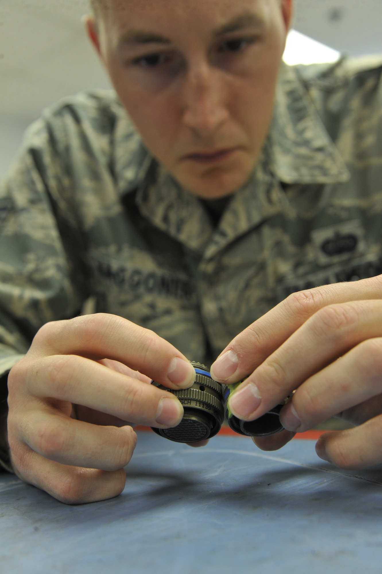 U.S. Air Force Staff Sgt. Jaret Waggoner, 72nd Test and Evaluation Squadron network systems administrator, inspects cannon plugs at Whiteman Air Force Base, Mo., Oct. 29, 2013. Cannon plugs are combined to transmit data and ensure there is a secure connection within the aircraft. (U.S. Air Force photo by Airman 1st Class Keenan Berry/Released)
