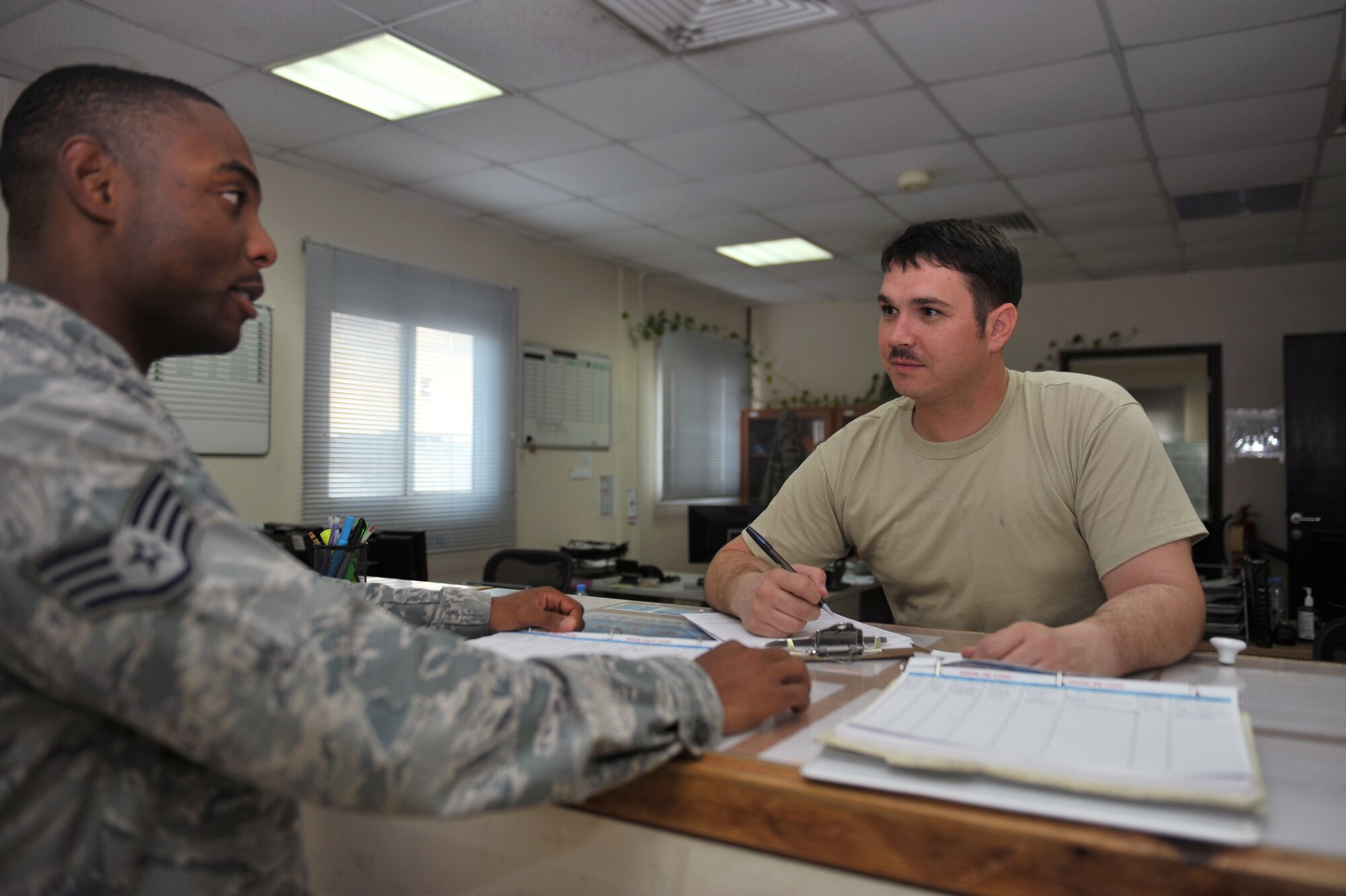 Staff Sgt. Xaviour Campbell speaks to Tech Sgt. John Hoffman at the vehicle leasing customer service counter in Southwest Asia, Nov. 14, 2013.  Campbell is a 379th Expeditionary Logistics Readiness Squadron lease vehicle management journeyman from RAF Mildenhall, England and an Ochorios, Jamaica, native. Hoffman is the 379th ELRS lease vehicle management NCO in charge is deployed from Joint Base Andrews and is a Westminster, Colo., native. (U.S. Air Force photo/Master Sgt. David Miller)