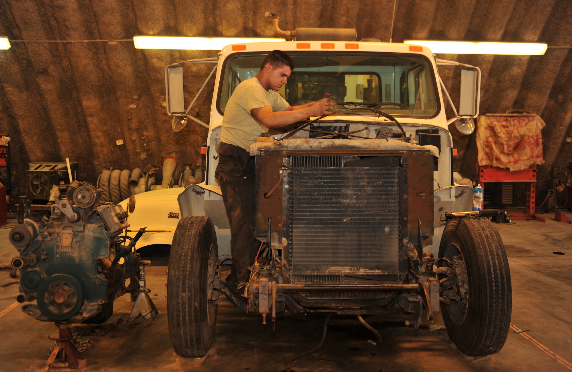 Airman 1st Class Scott Middlebrooks connect the upper radiator hose to the engine after an engine swap in a street sweeper in Southwest Asia, Nov. 14, 2013. Installing a used running engine saves time and money over the alternative of installing a new engine. Middlebrooks is a 379th Expeditionary Logistics Readiness Squadron vehicle equipment journeyman deployed from Altus Air Force Base, Okla., and a McDonough, Ga., native. (U.S. Air Force photo/Master Sgt. David Miller)