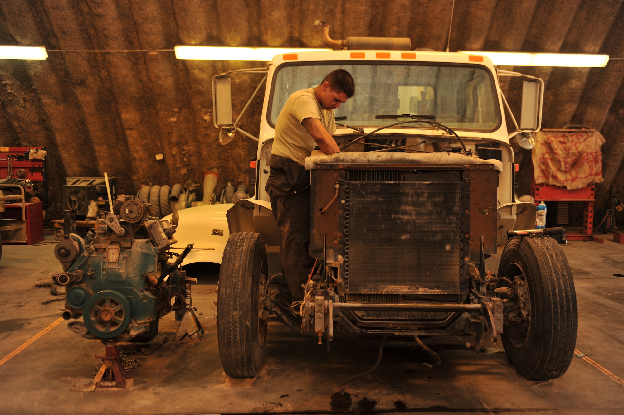 Airman 1st Class Scott Middlebrooks connects the lower radiator hose to the engine after an engine swap in a street sweeper in Southwest Asia, Nov. 14, 2013. Installing a used running engine saves time and money over the alternative of installing a new engine. Middlebrooks is a 379th Expeditionary Logistics Readiness Squadron vehicle equipment journeyman deployed from Altus Air Force Base, Okla., and a McDonough, Ga., native. (U.S. Air Force photo/Master Sgt. David Miller)