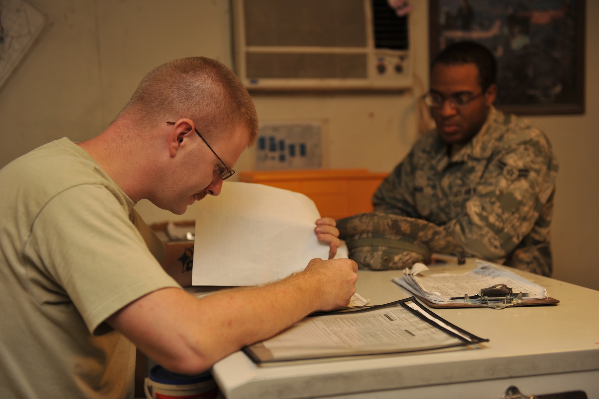 Staff Sgt. Scott Wyman reviews vehicle paperwork from Airman 1st Class Joseph Johnson in Southwest Asia, Nov. 14, 2013. Prior to turn in and pick-up of vehicles all paperwork is reviewed to ensure all issues are addressed. Wyman is a 379th Expeditionary Logistics Readiness Squadron customer service supervisor deployed from Misawa Air Base, Japan, and a Fort Worth, Texas, native. Johnson is an 8th Expeditionary Air Mobility Squadron air transporter deployed from Ramstein, Air Base, Germany, and a Morgan City, La., native. (U.S. Air Force photo/Master Sgt. David Miller)