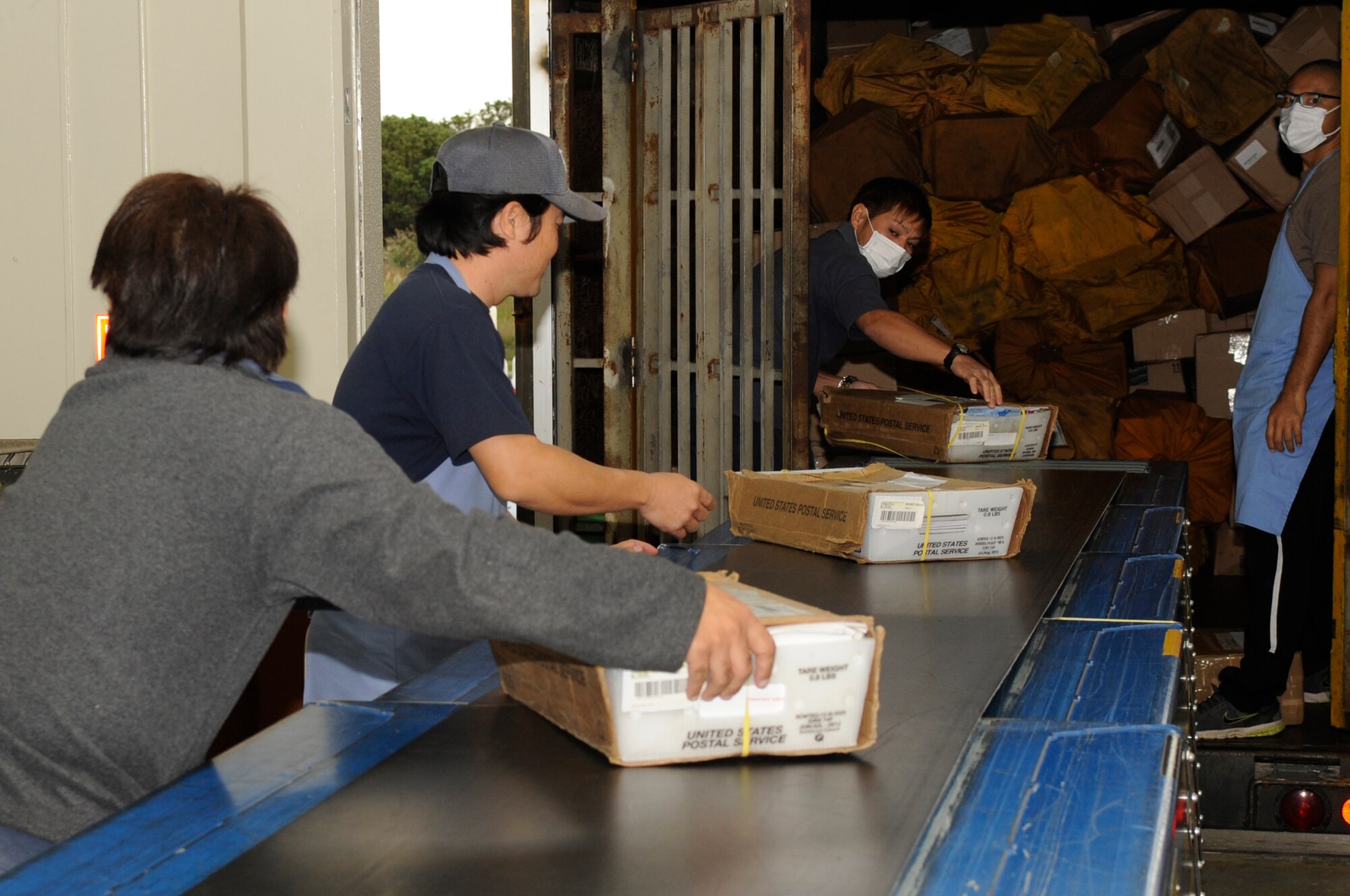 Japanese employees from the post office at Kadena Air Base, Japan, unload packages from a truck Nov. 19, 2013. During the holiday season, the post office processes 500 to 600 packages daily. (U.S. Air Force photo by Senior Airman Marcus Morris)