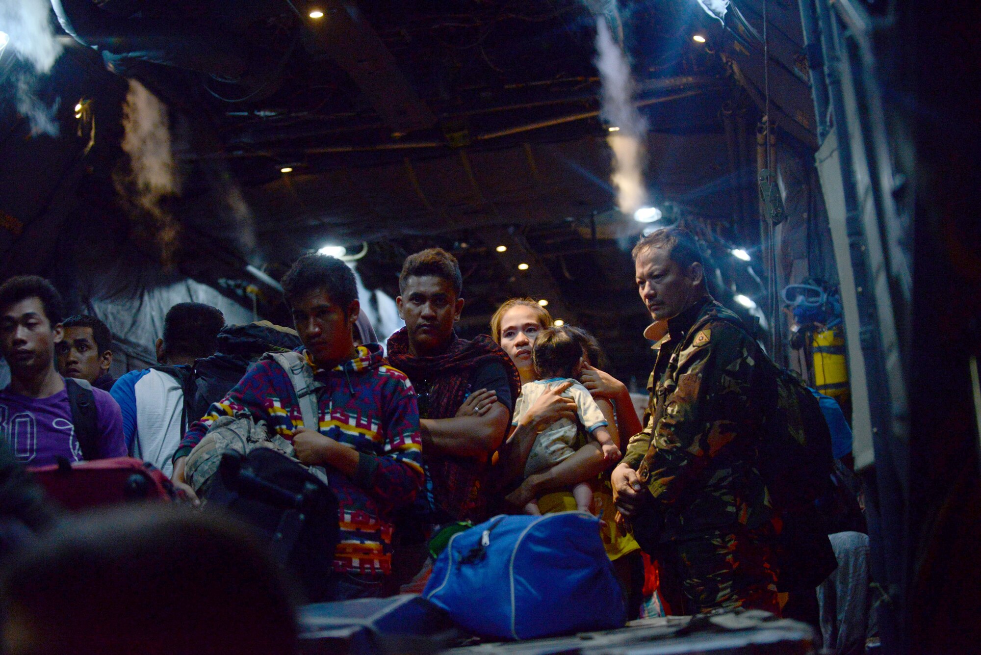 A Philippine army soldier watches as evacuees from Tacloban Airport prepare to exit an Air Force C-130 Hercules aircraft Nov. 19, 2013, at Villamor Air Base, Republic of the Philippines, during Operation Damayan. The aircraft carry approximately 120 passengers per evacuation mission.