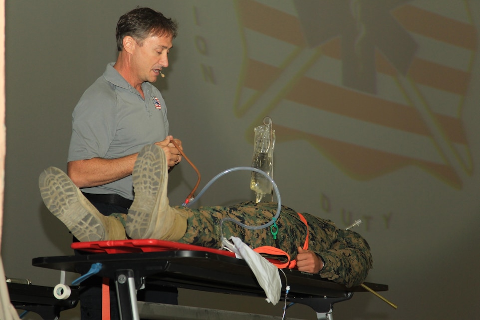 Vincent Easevoli, firefighter paramedic, Stay Alive From Education Program, uses Private First Class Trevor Mixon, student, Marine Corps Communcations-Electronics School, to explain the lifesaving process taken after a vehicle accident to educate MCCES students about safe driving at the base theater Nov. 19, 2013.