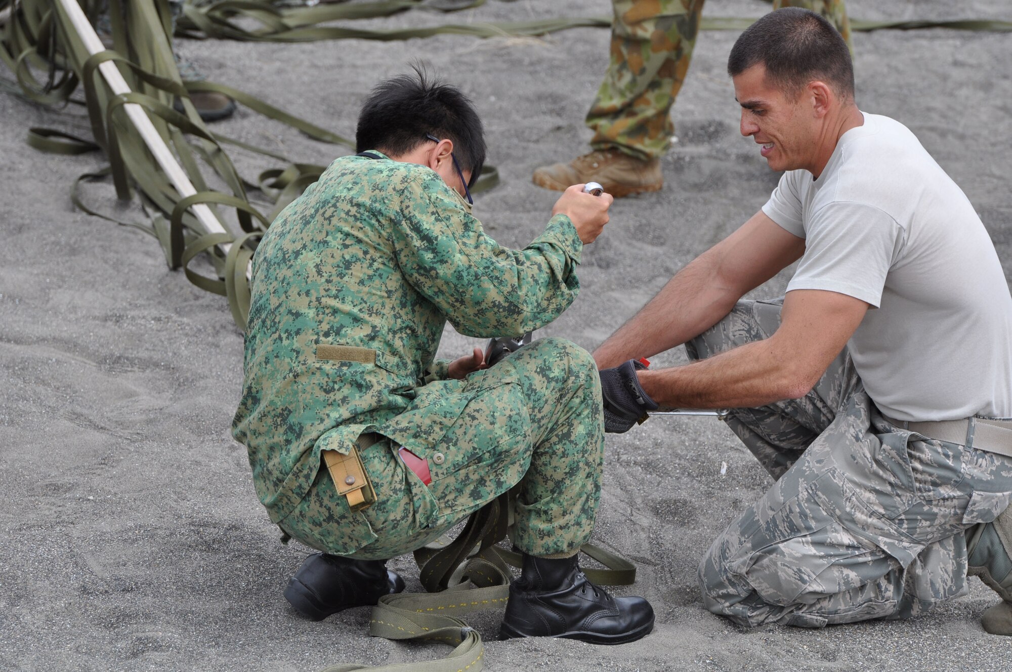 OHAKEA, New Zealand -- Republic of Singapore Armed Forces Staff Sgt. Joseph Ho (left) and United States Air Force Tech. Sgt. Steve Wright work together to untangle the parachute lines from tactically-air-dropped cargo which landed just east of the drop zone during Exercise Kiwi Flag Nov. 14 at the New Zealand Defence Force Raumi Drop Zone near Ohakea, New Zealand. Kiwi Flag personnel are supporting Exercise Southern Katipo -- held on New Zealand’s South Island. (U.S. Air Force photo by Senior Master Sgt. Denise Johnson/Released)