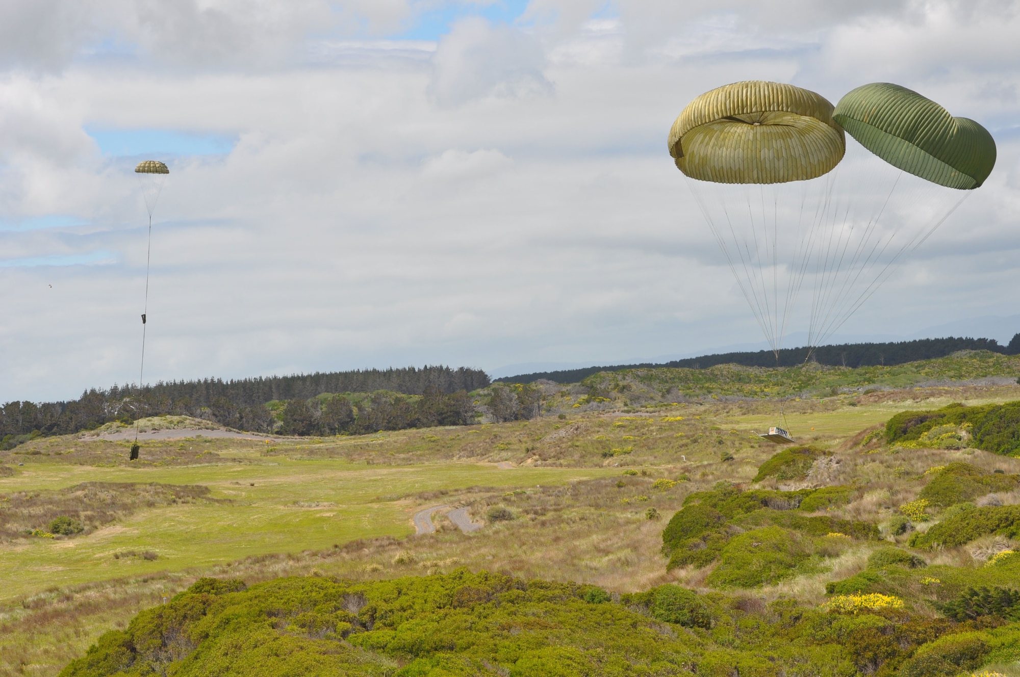 OHAKEA, New Zealand -- An extraction parachute (left) makes its way to ground safely away from the two G-11 main parachutes during a tactical air drop from the ramp of a Republic of Singapore Armed Forces C-130 Hercules during Exercise Kiwi Flag Nov. 14 at the New Zealand Defence Force Raumi Drop Zone near Ohakea, New Zealand. Kiwi Flag is a multilateral Royal New Zealand Air Force-sponsored tactical airlift exercise comprising air assets from the U.S. Air Force, RNZAF, Royal Australian Air Force, RSAF and French Armed Forces of New Caledonia. (U.S. Air Force photo by Senior Master Sgt. Denise Johnson/Released)