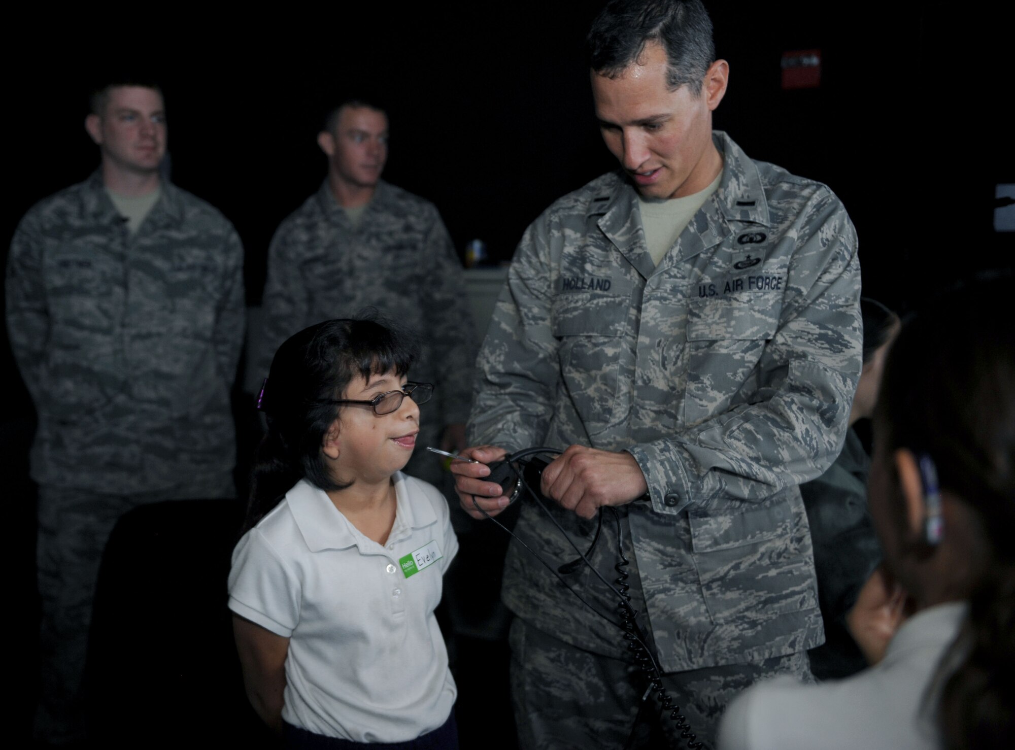 U.S. Air Force 1st Lt. Rolland Holland, 355th Operations Support Squadron airfield operations manager, holds the microphone for the air traffic control tower simulator as Evelyn Chavarin, Arizona School for the Deaf and the Blind third grade student, speaks during a school tour at Davis-Monthan Air Force Base, Ariz., Nov. 14, 2013. The ten students that participated in the tour attend local public schools, but receive weekly training from ASDB teachers. (U.S. Air Force photo by Airman 1st Class Saphfire Cook/released)