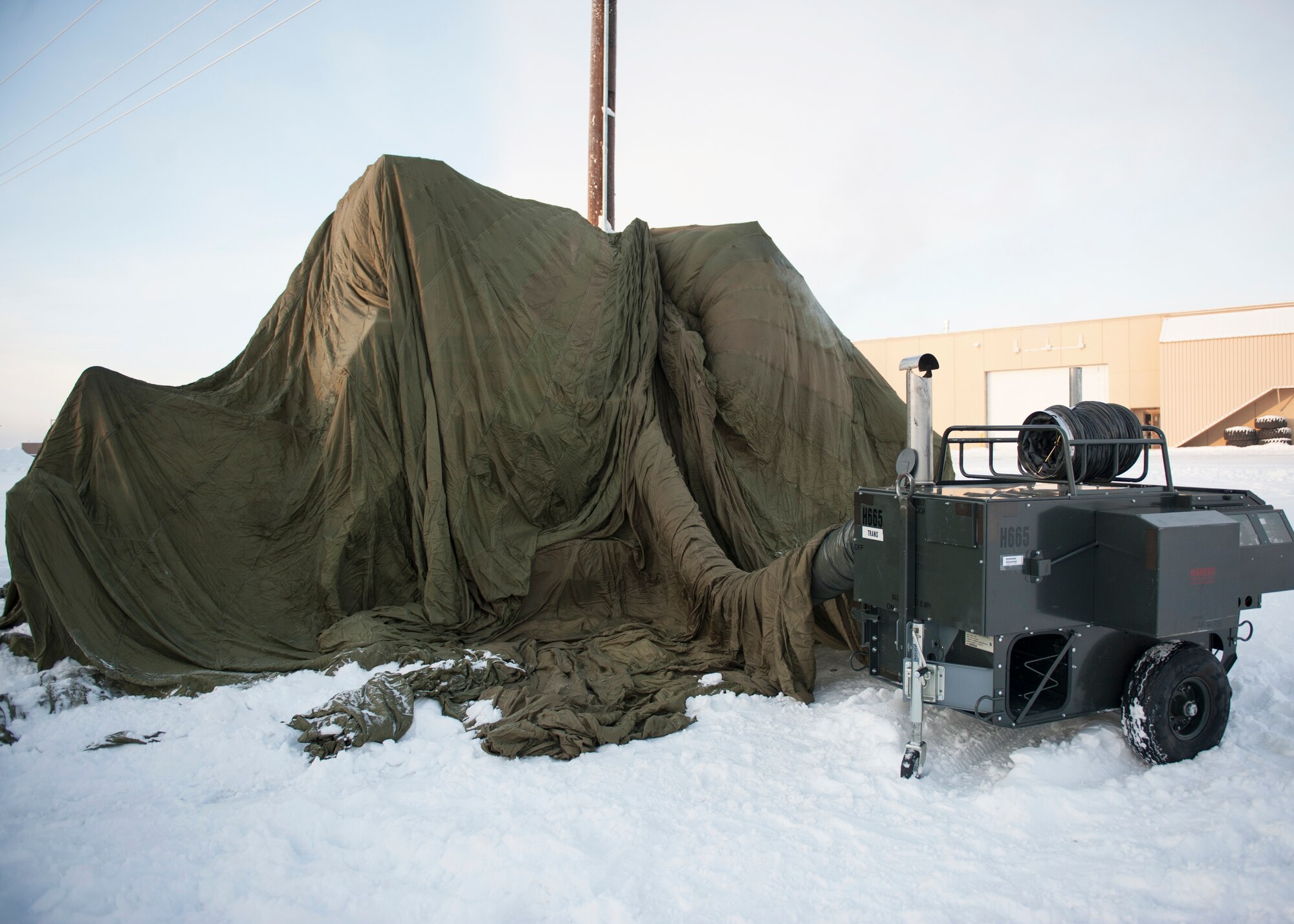 A portable heater warms a frozen bulldozer underneath a giant parachute Nov. 19, 2013, Eielson Air Force Base, Alaska. The parachute is placed as a barrier to trap heat in order to thaw the frozen vehicle. (U.S. Air Force photo by Senior Airman Ashley Nicole Taylor/Released)